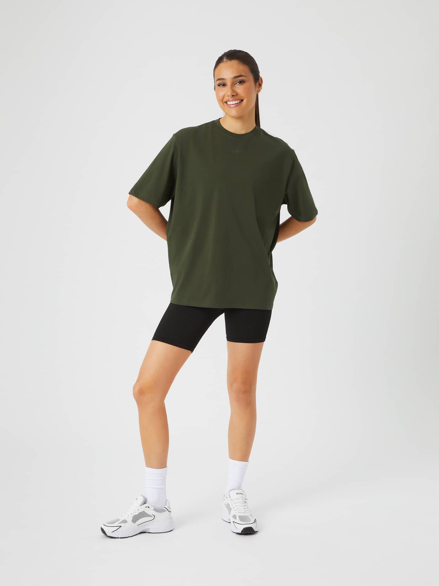 Full-body front view of a woman wearing the Björn Borg Studio Oversized T-Shirt in Duffel Bag (Green) for training. - Image 3