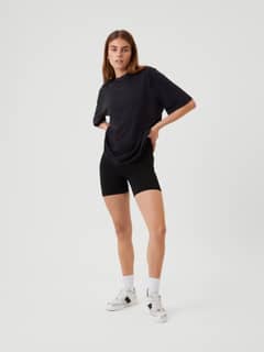 Full-body front view of a model wearing the Studio Oversized T-Shirt in Black Beauty (Black) with a tonal logo for training. - Image 6