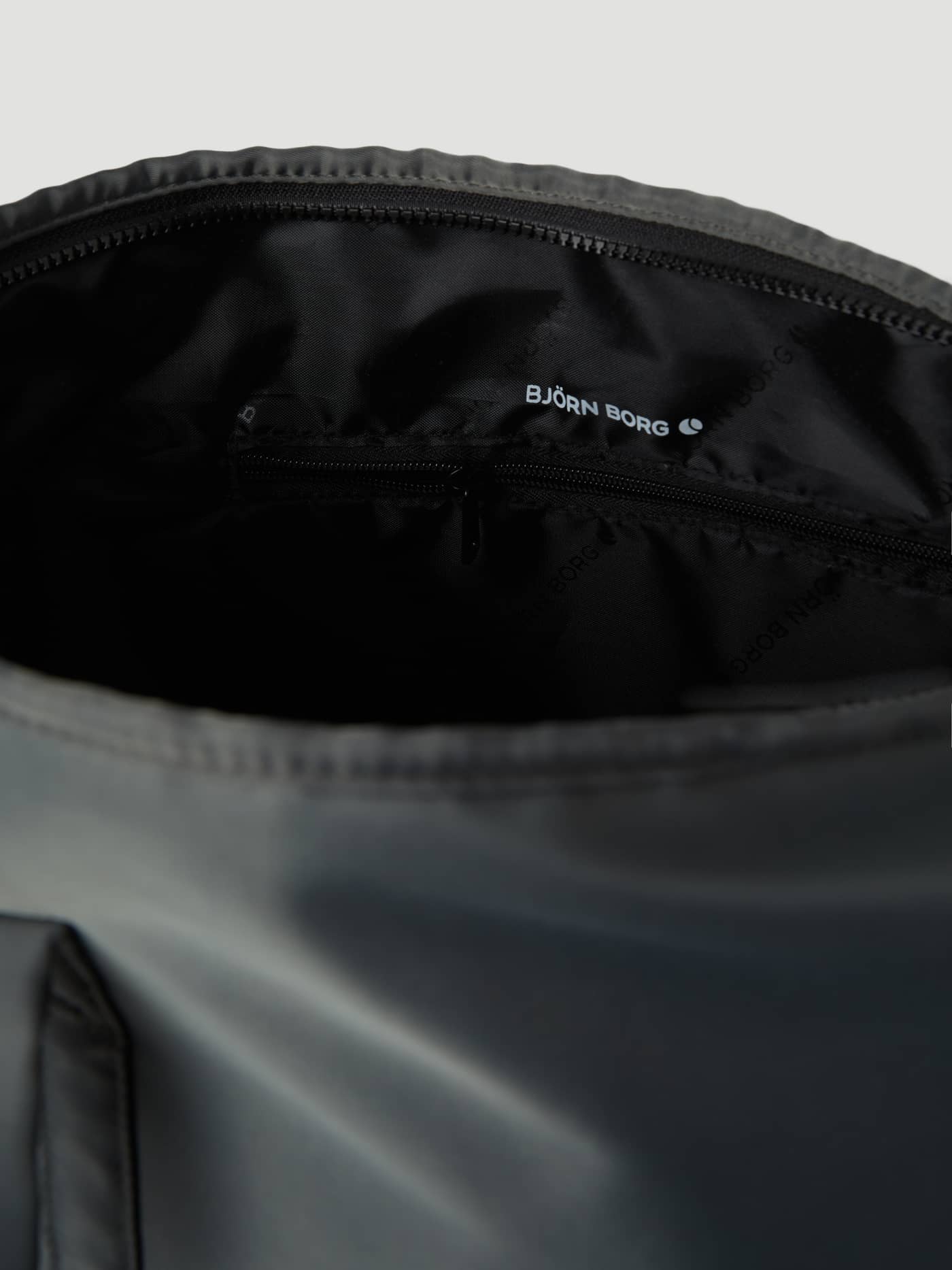 Interior of the Sthlm Leisure Shopper in Olive Night (Green) with a zippered pocket and white logo on tonal polyester lining. - Image 4