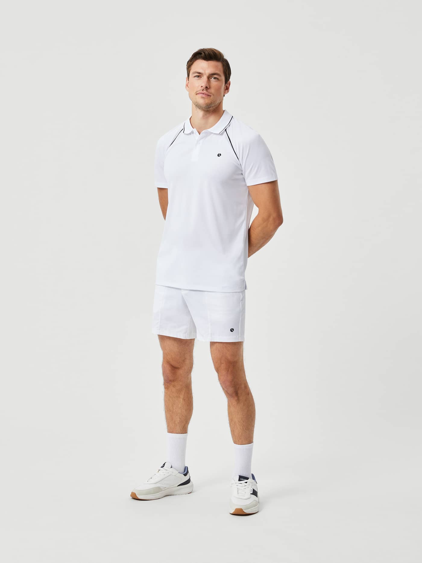 Full-body front view of a man in the recycled Ace Racquet Polo in Brilliant White (White) with black tennis logo and piping. - Image 3