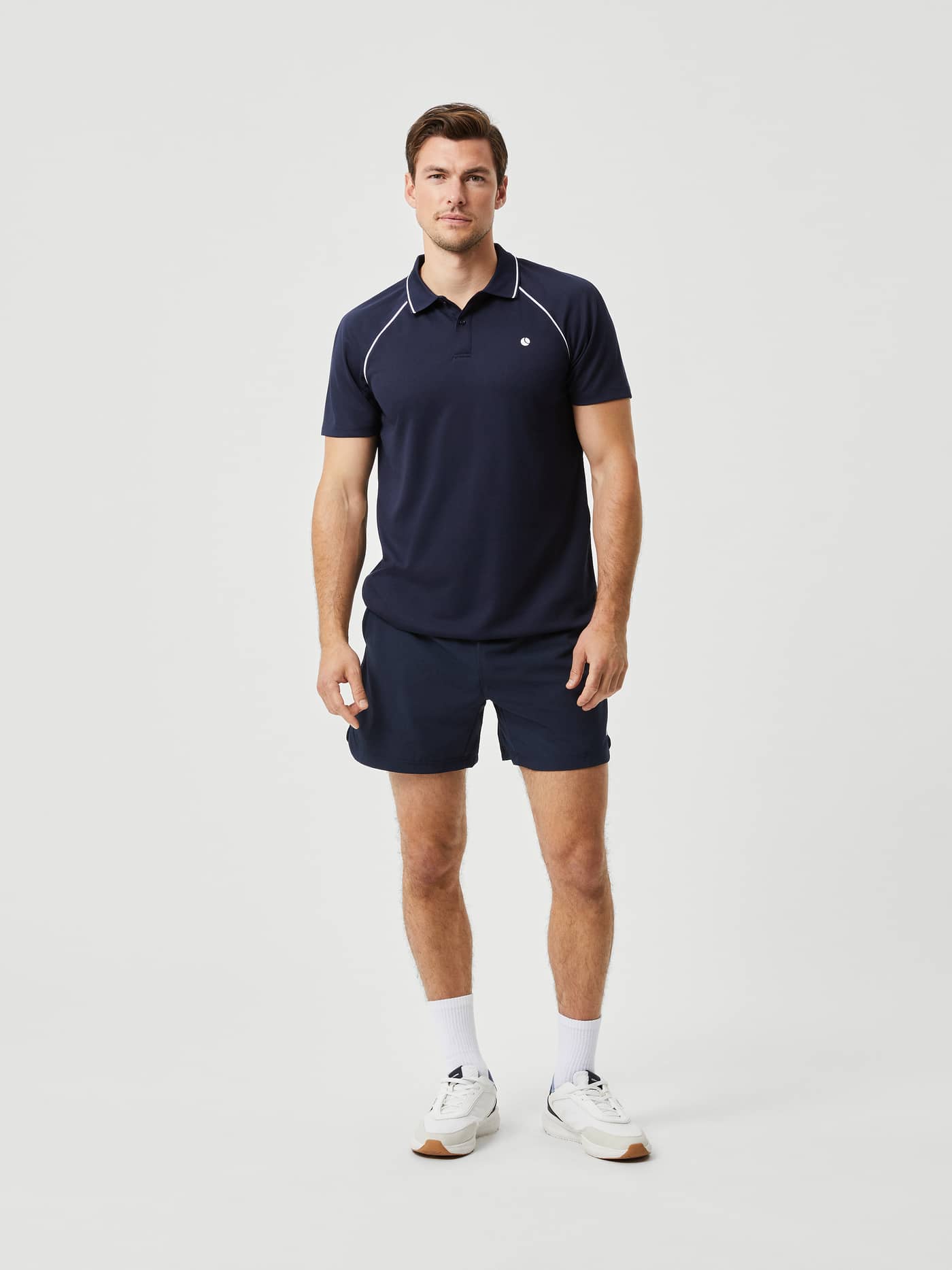 Full-body front view of a man wearing the Björn Borg Ace Racquet Polo in Night Sky (Blue) with a white tennis logo. - Image 3