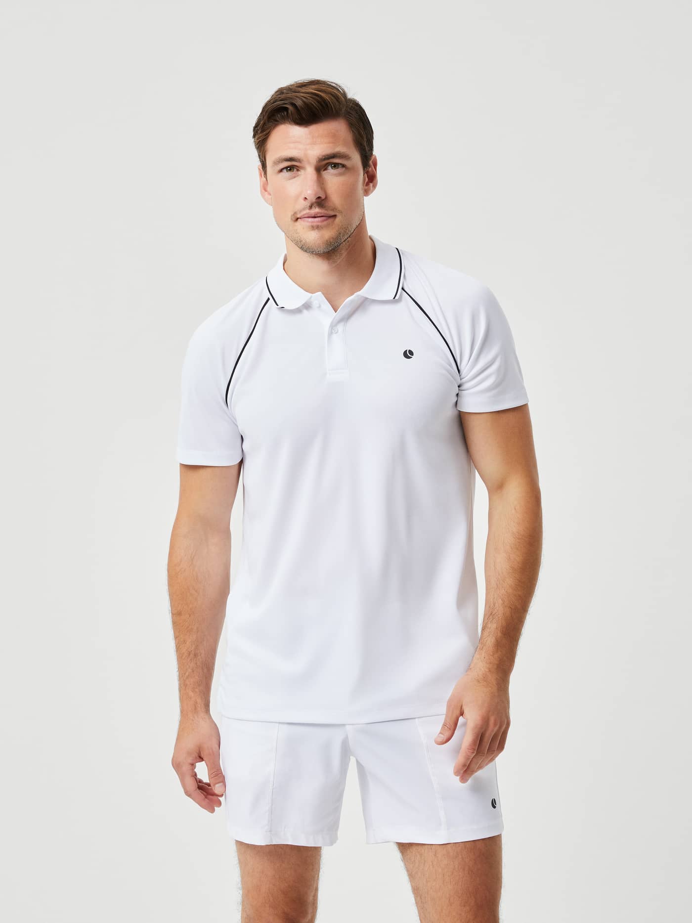 Front view of a man in the Björn Borg Ace Racquet Polo in Brilliant White (White), a performance tennis top with a dark logo. - Image 1