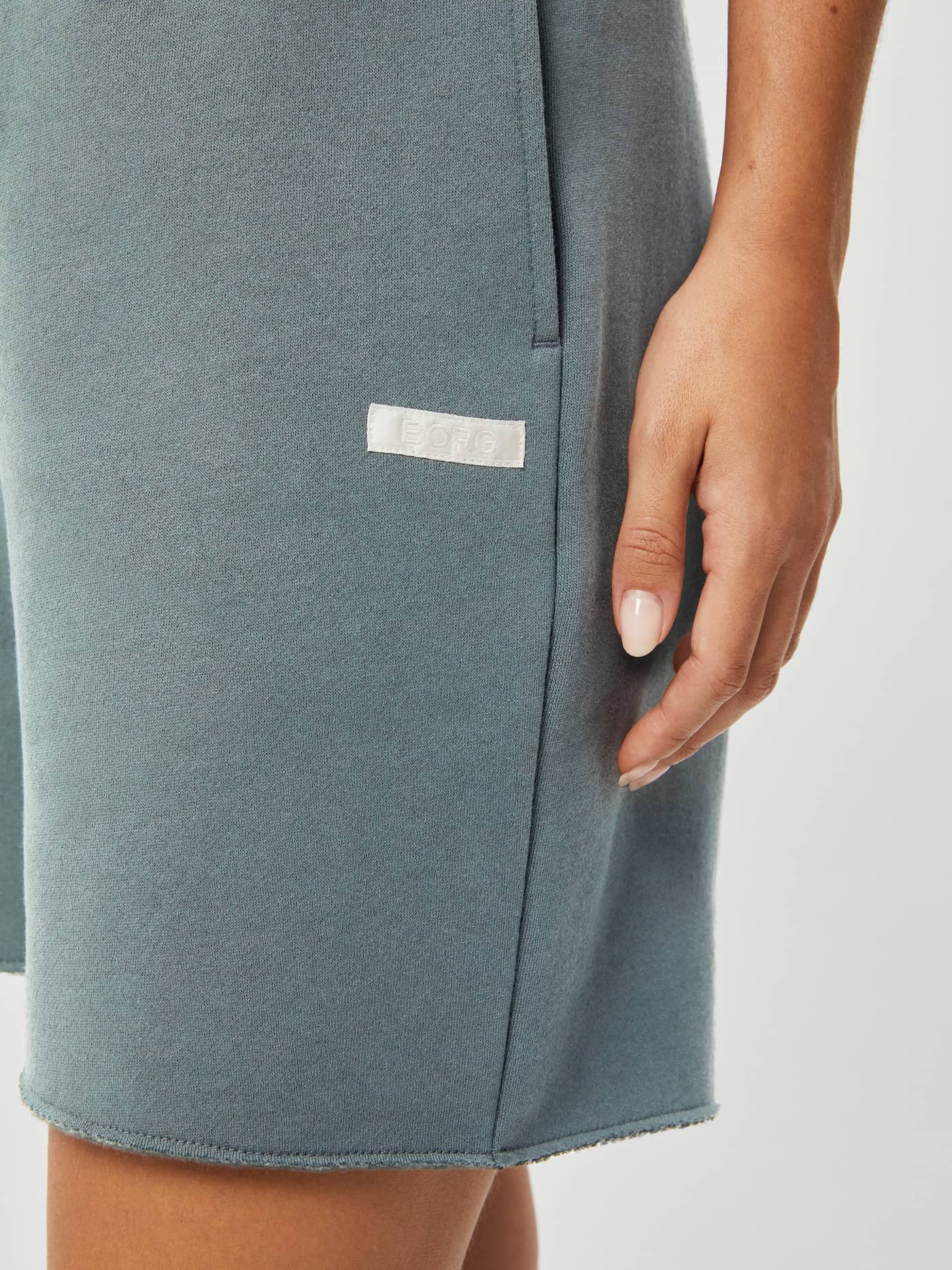 Studio Oversized Shorts i Gray Mist (Blå) med hvit BORG-logolapp i sateng og sidelomme, nærbilde. - Image 4