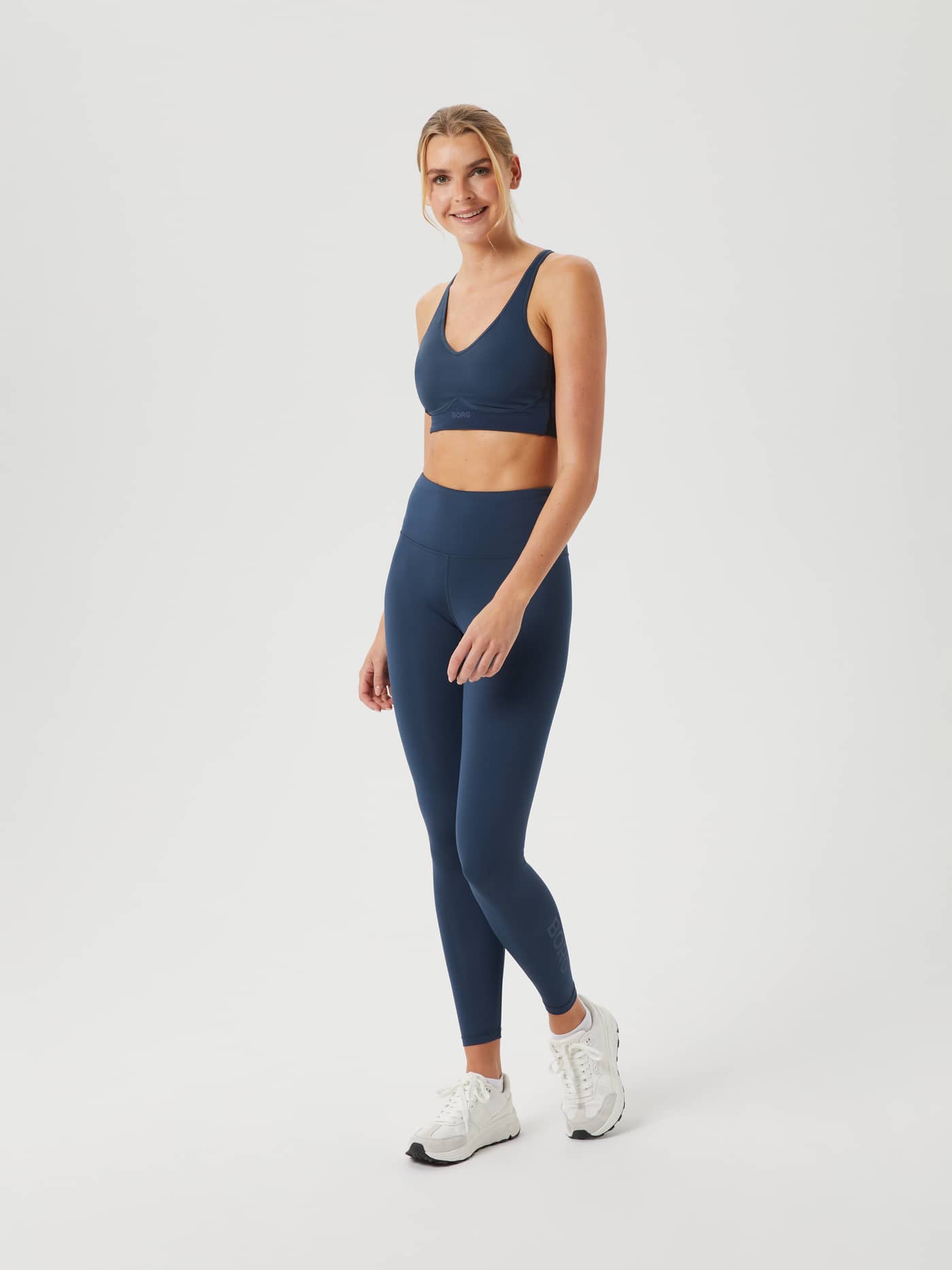 Full-body view of a woman wearing the slim-fit Borg Logo Tights in Midnight Navy (Navy) for high-performance training. - Image 1