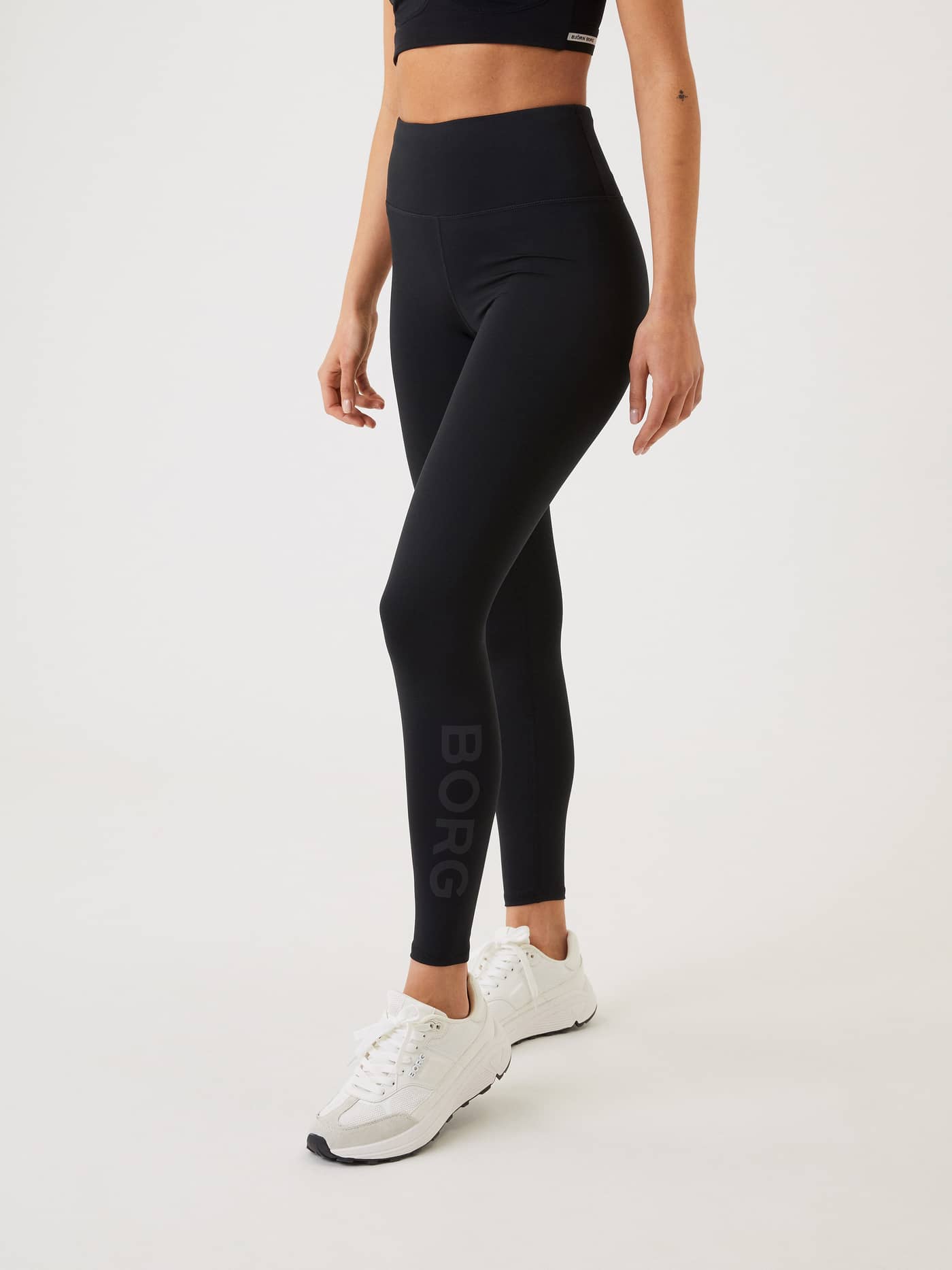Three-quarter view of a model in high-waisted Borg Logo Tights in Black Beauty (Black) for training with a grey logo. - Image 3