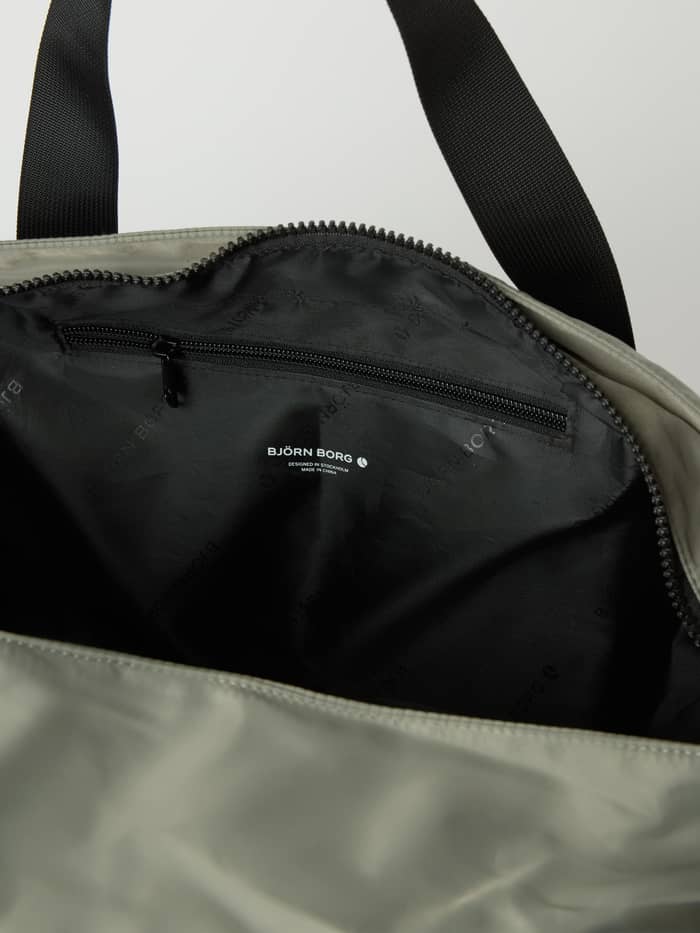 Inside the Agave Green (Green) Borg Classic Tote 27L training bag, featuring a zippered pocket and black logo pattern lining. - Image 4