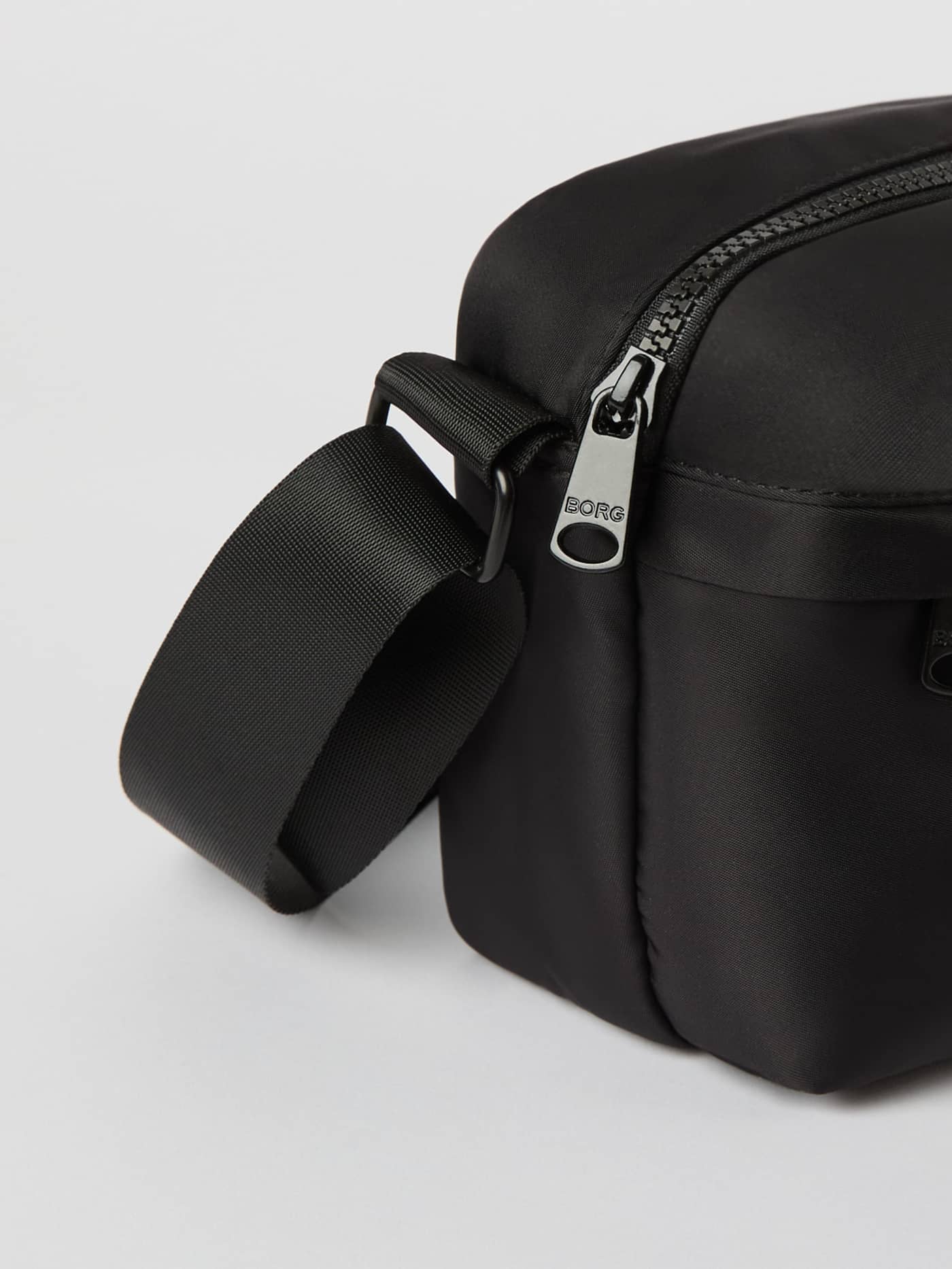 Detailed close-up of the polyester Borg Daily Crossover Bag in Black Beauty (Black), featuring the silver BORG logo. - Image 3