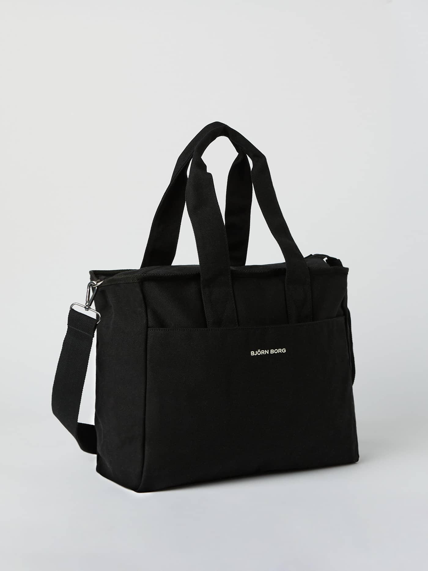 Front view of the Studio Canvas Tote 27L in Black Beauty (Black) featuring durable cotton canvas, a white logo, and straps. - Image 2