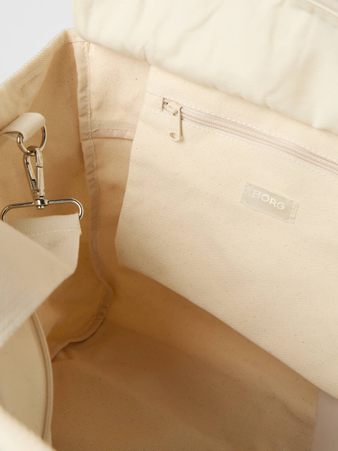 Interior view of the cotton Studio Canvas Tote 27L in Egret (White) showing the zippered pocket and white BORG logo. - Image 4