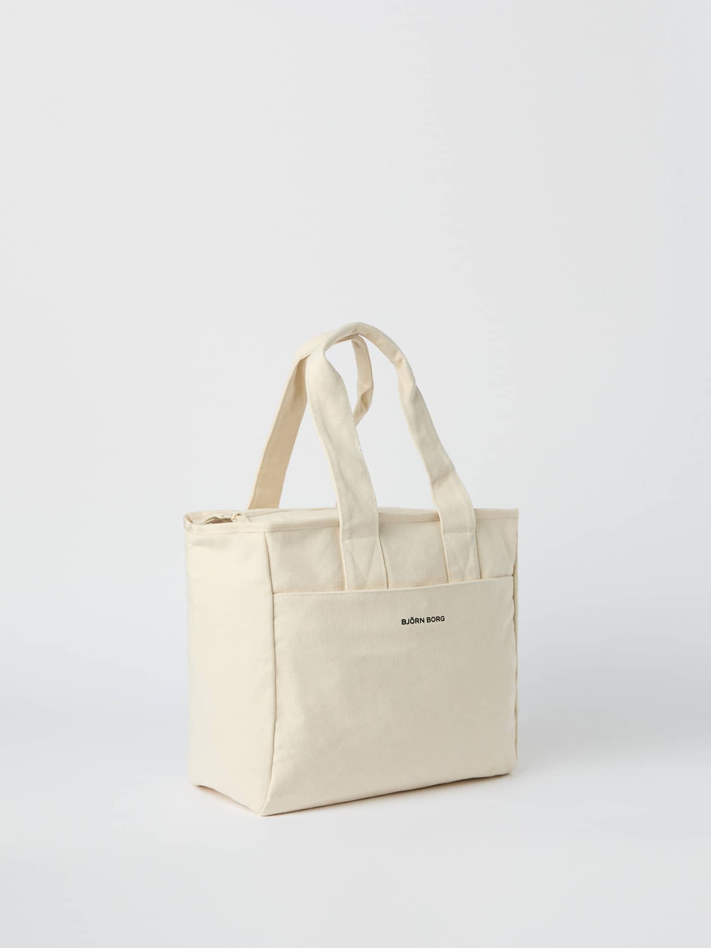 Studio Canvas Tote 27L in Egret (White), a durable cotton canvas shopper bag with a black logo and sturdy hand straps. - Image 2