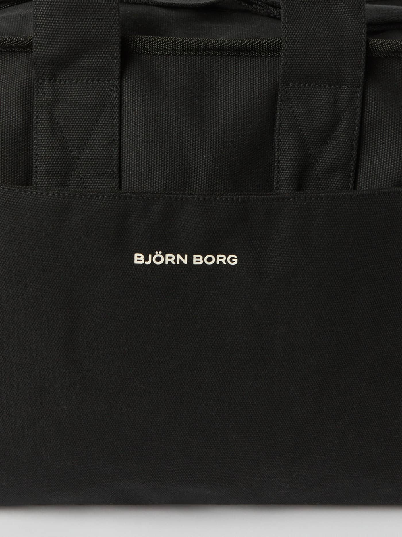 Detailed close-up of the Studio Canvas Tote 27L in Black Beauty (Black) cotton canvas with a white Björn Borg logo. - Image 4