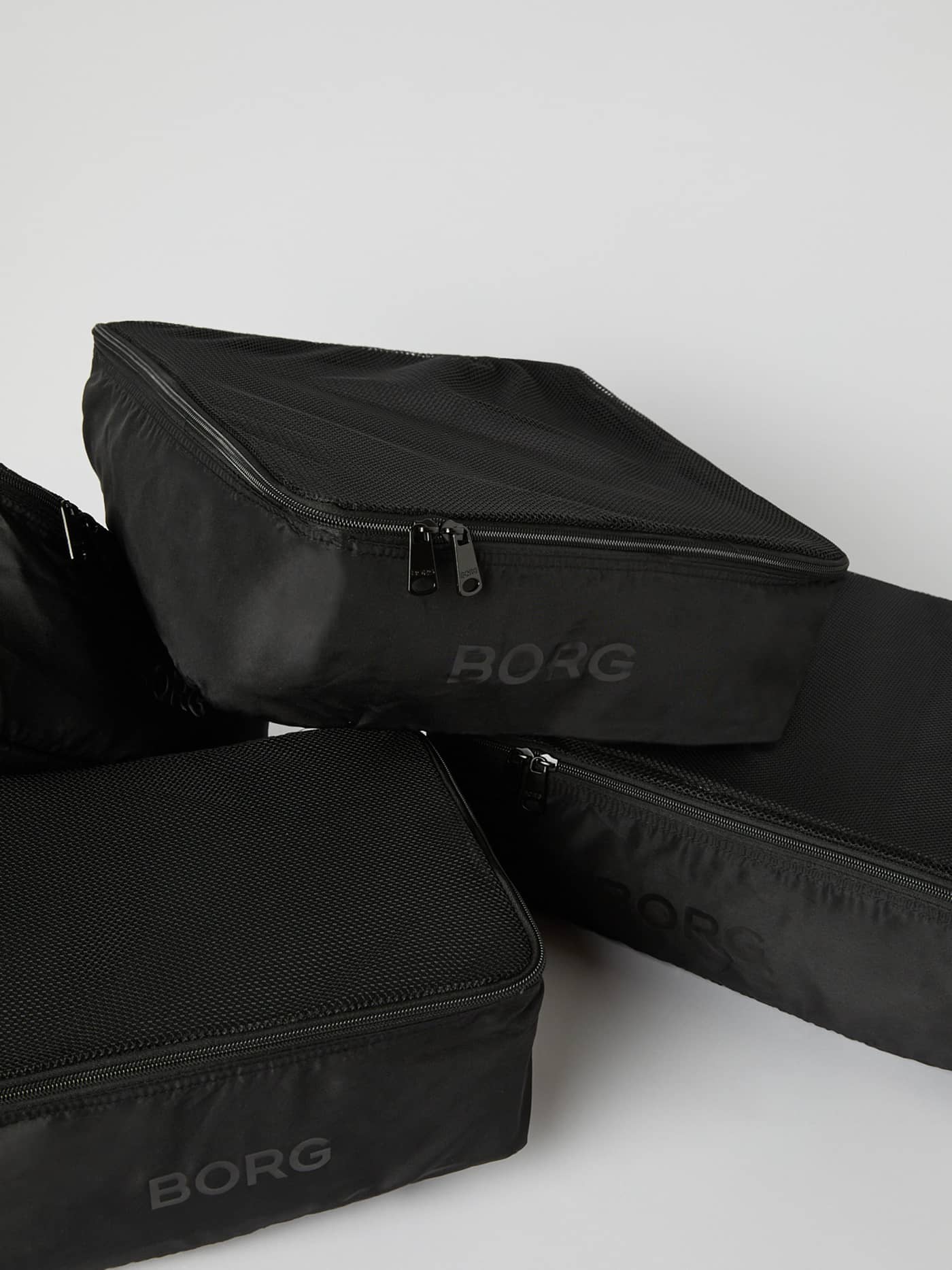 A stack of the Borg Travel Garment Cases in Black Beauty (Black) with mesh ventilation panels and a tonal logo. - Image 4