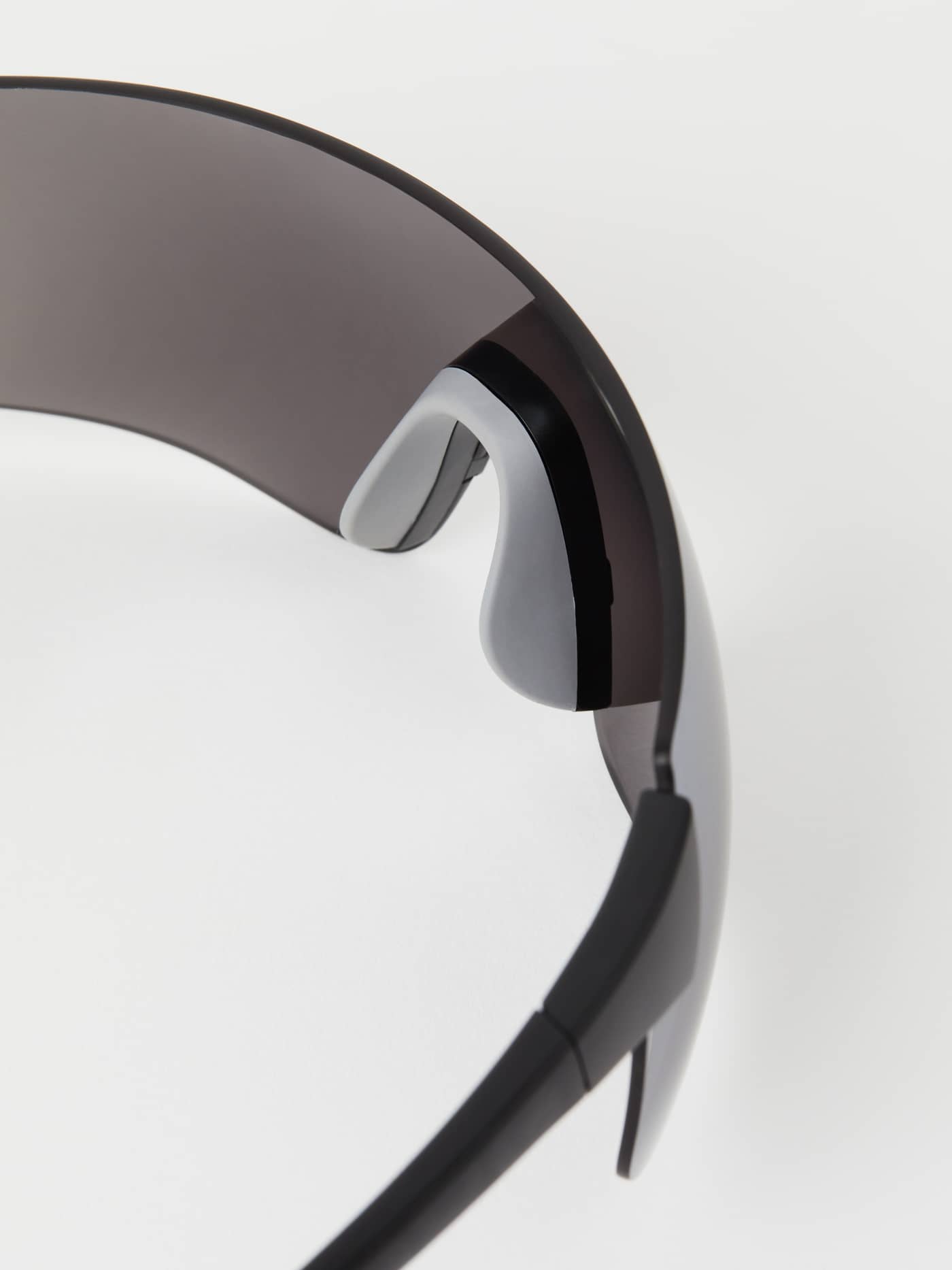 Detailed close-up of the adjustable grey MEGOL rubber nose pads on the black Running Sunglasses for running performance. - Image 5