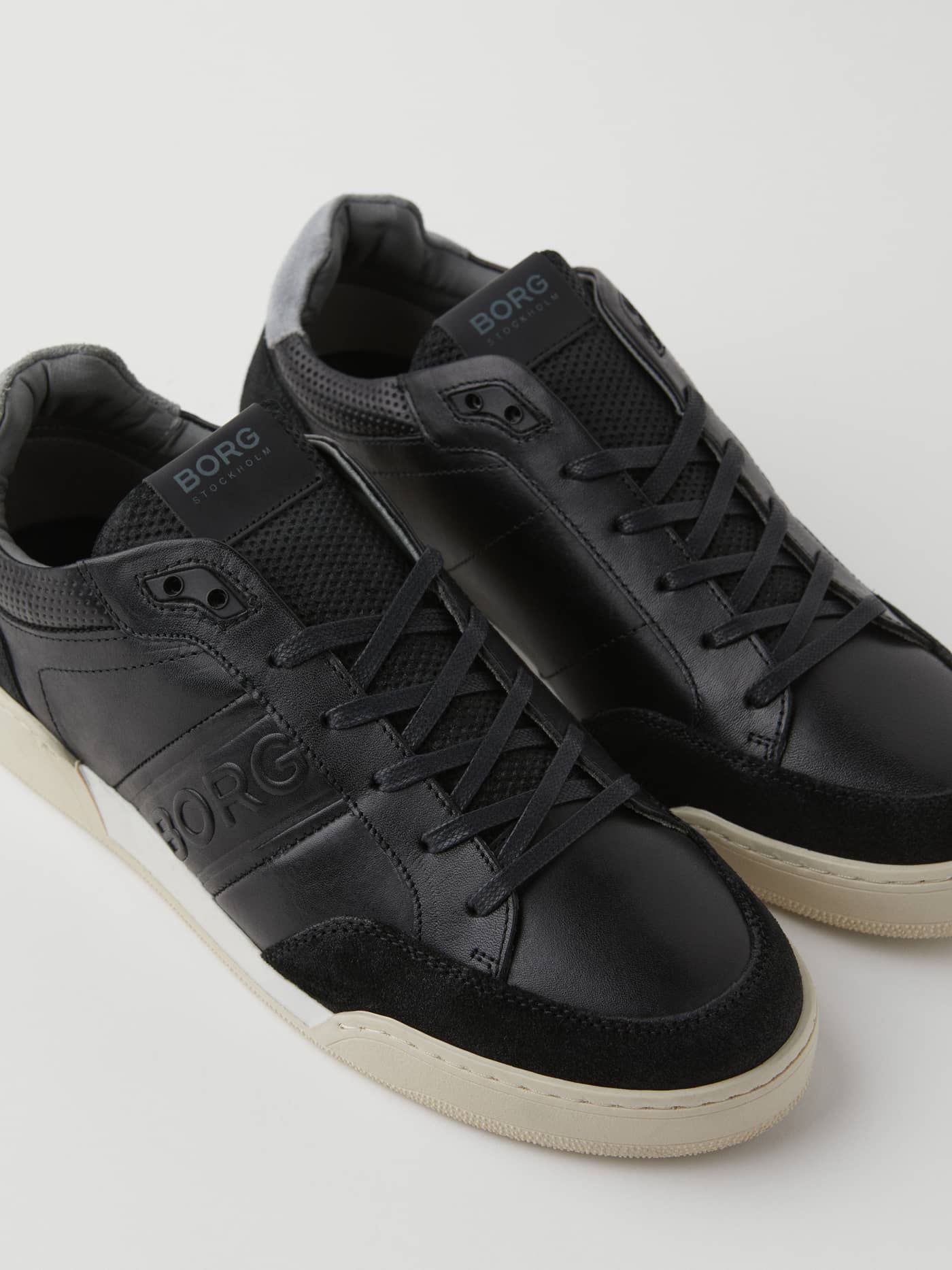 Angled close-up of the tennis-style Men's Leather Sneaker Sl200 in Black, featuring leather and suede with a tonal logo. - Image 3