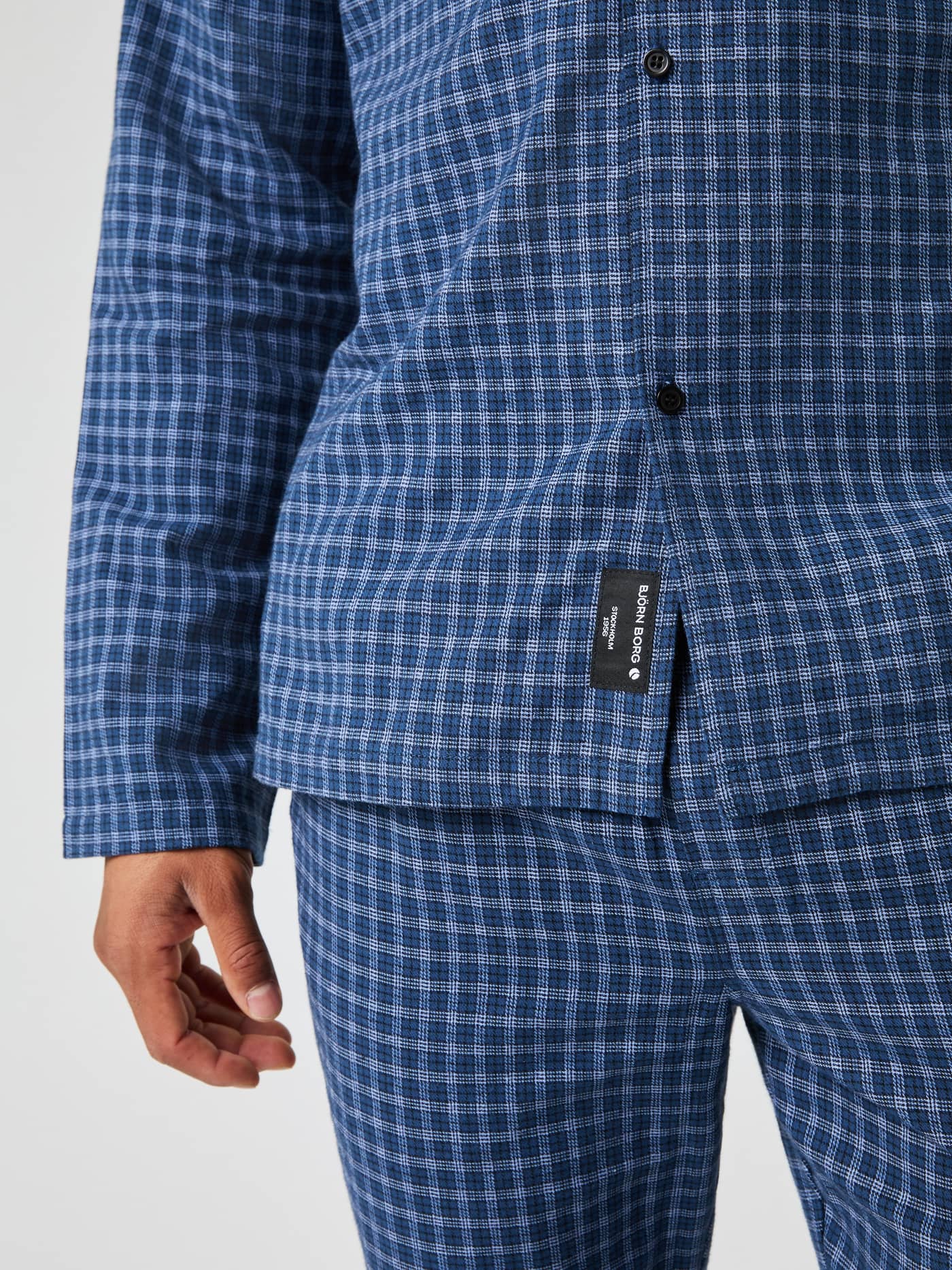 Close-up of the Björn Borg Core Flannel Pyjama Shirt in blue check, showing the fabric texture and the logo label at the hem. - Image 5