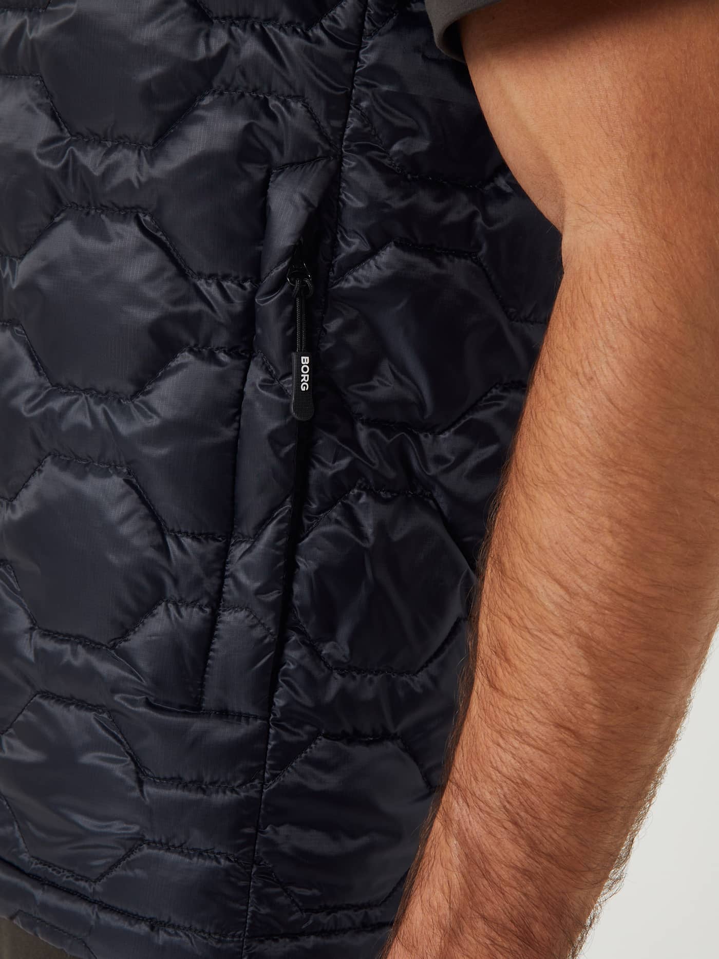 Primer plano del Borg Down Liner Vest acolchado ripstop en Black Beauty (Negro) con bolsillo lateral y logo blanco. - Image 5