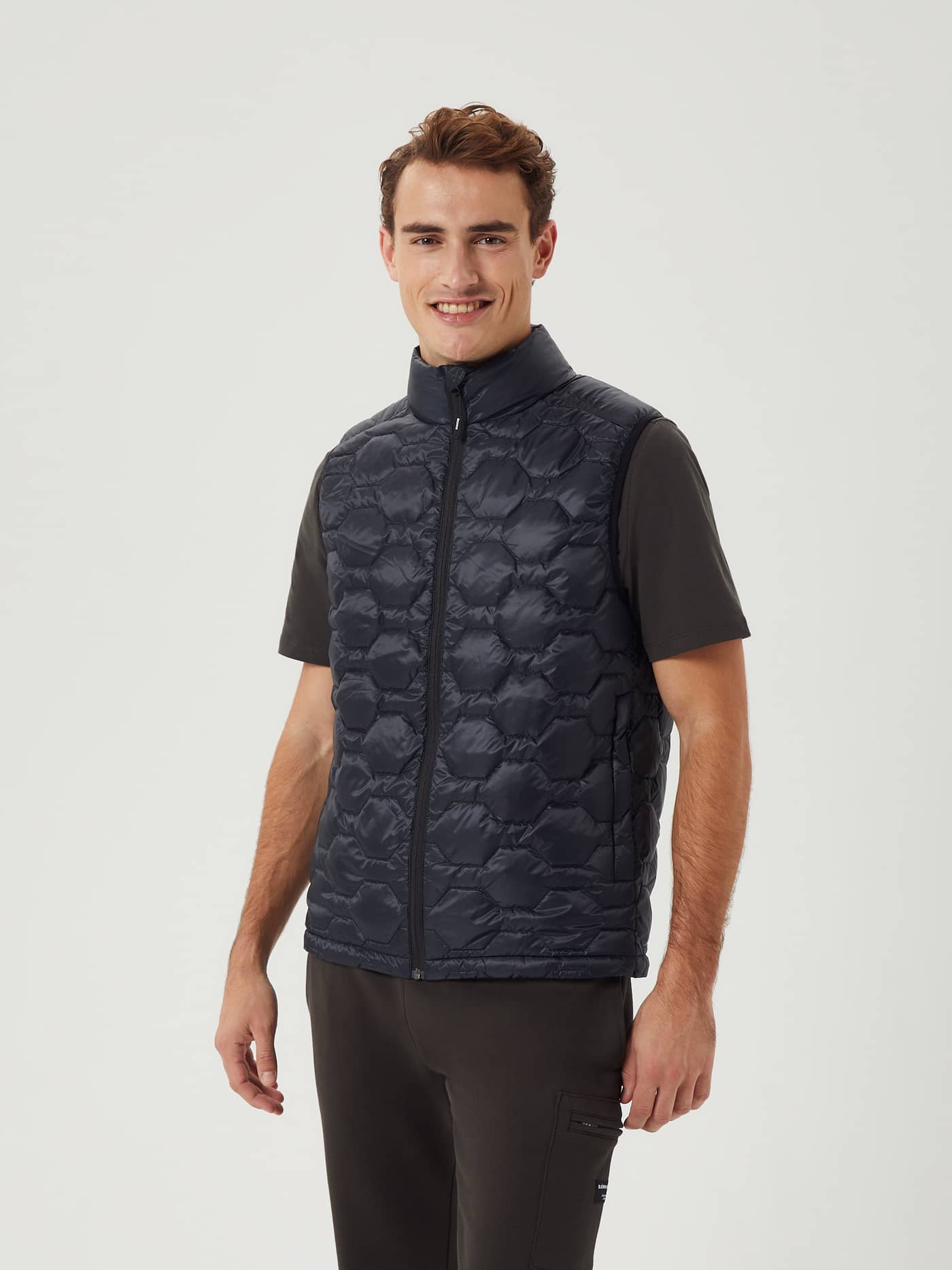 Vista frontal de un hombre con el Borg Down Liner Vest en Black Beauty (Negro) de diseño acolchado aislante. - Image 2
