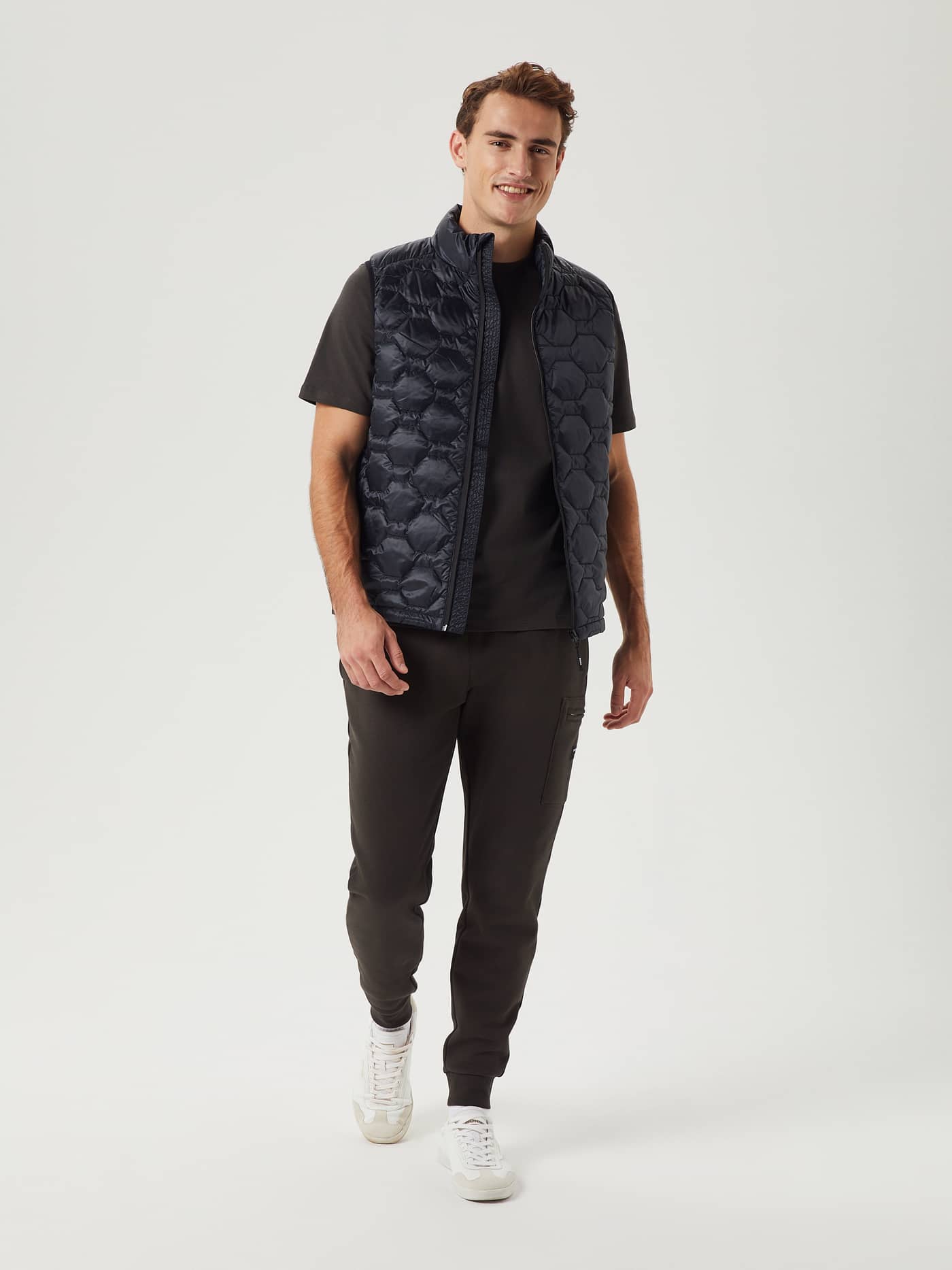 Vista frontal de cuerpo entero de un hombre con el funcional Borg Down Liner Vest en Black Beauty (Negro) y joggers a juego. - Image 4