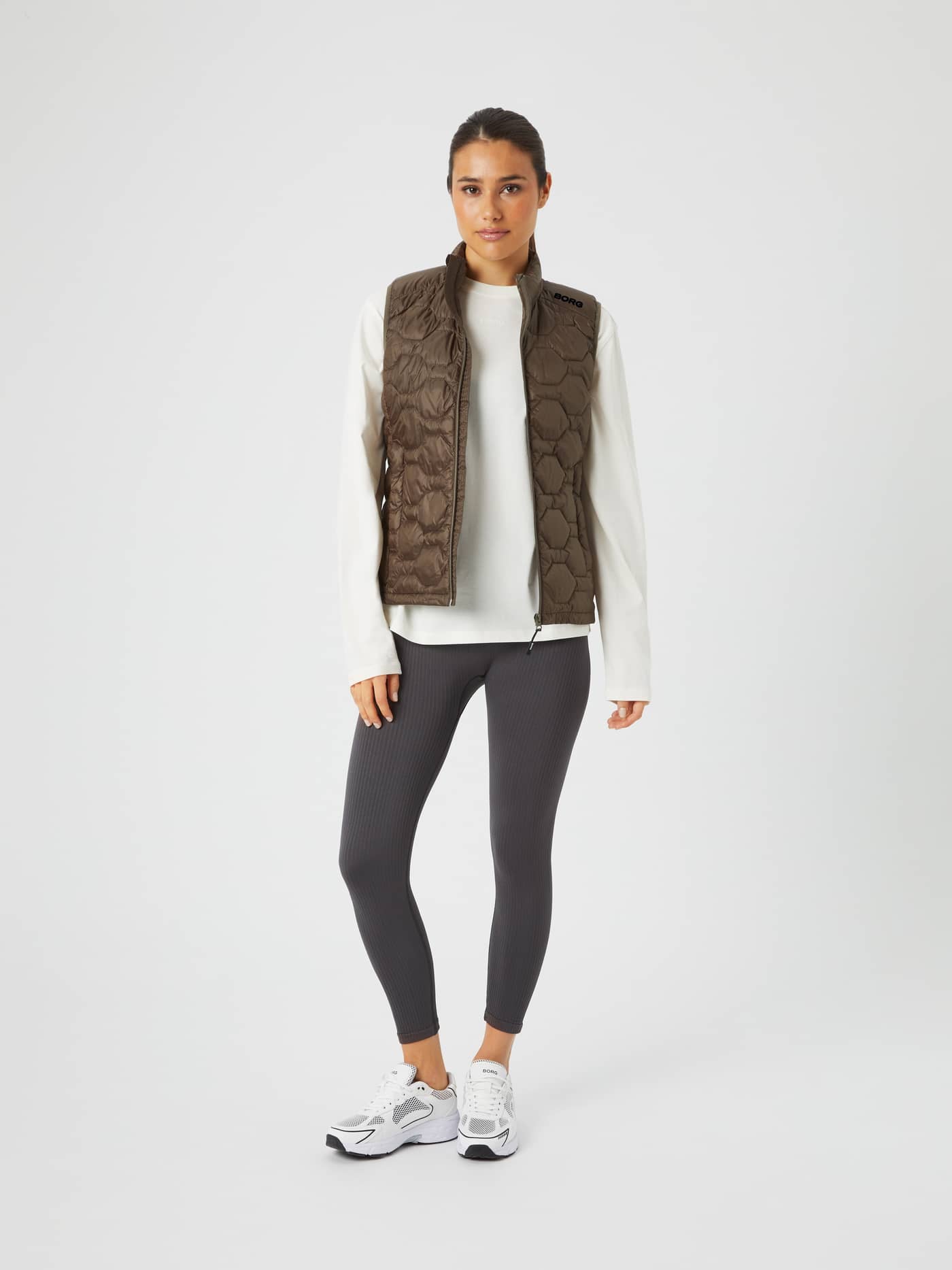 Full-body front view of a woman wearing the Tarmac (Brown) Borg Down Liner Vest with a black logo and regular fit. - Image 3