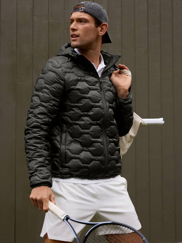 Framifrån på en man i en quiltad Borg Down Liner Jacket i Black Beauty (Svart) på en tennisbana, perfekt för tennis.