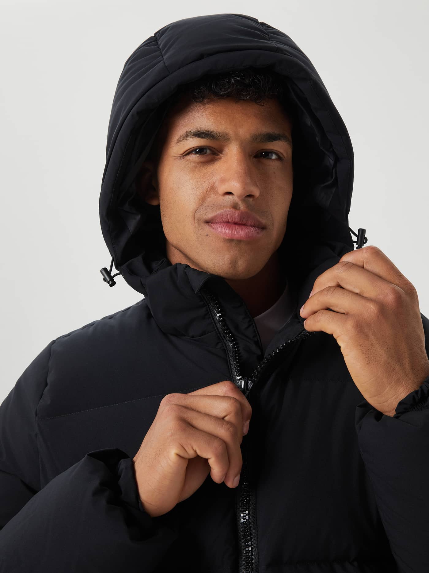 Close-up front view of a man wearing the Björn Borg Centre Puffer Jacket in Black Beauty (Black) with the hood up. - Image 4