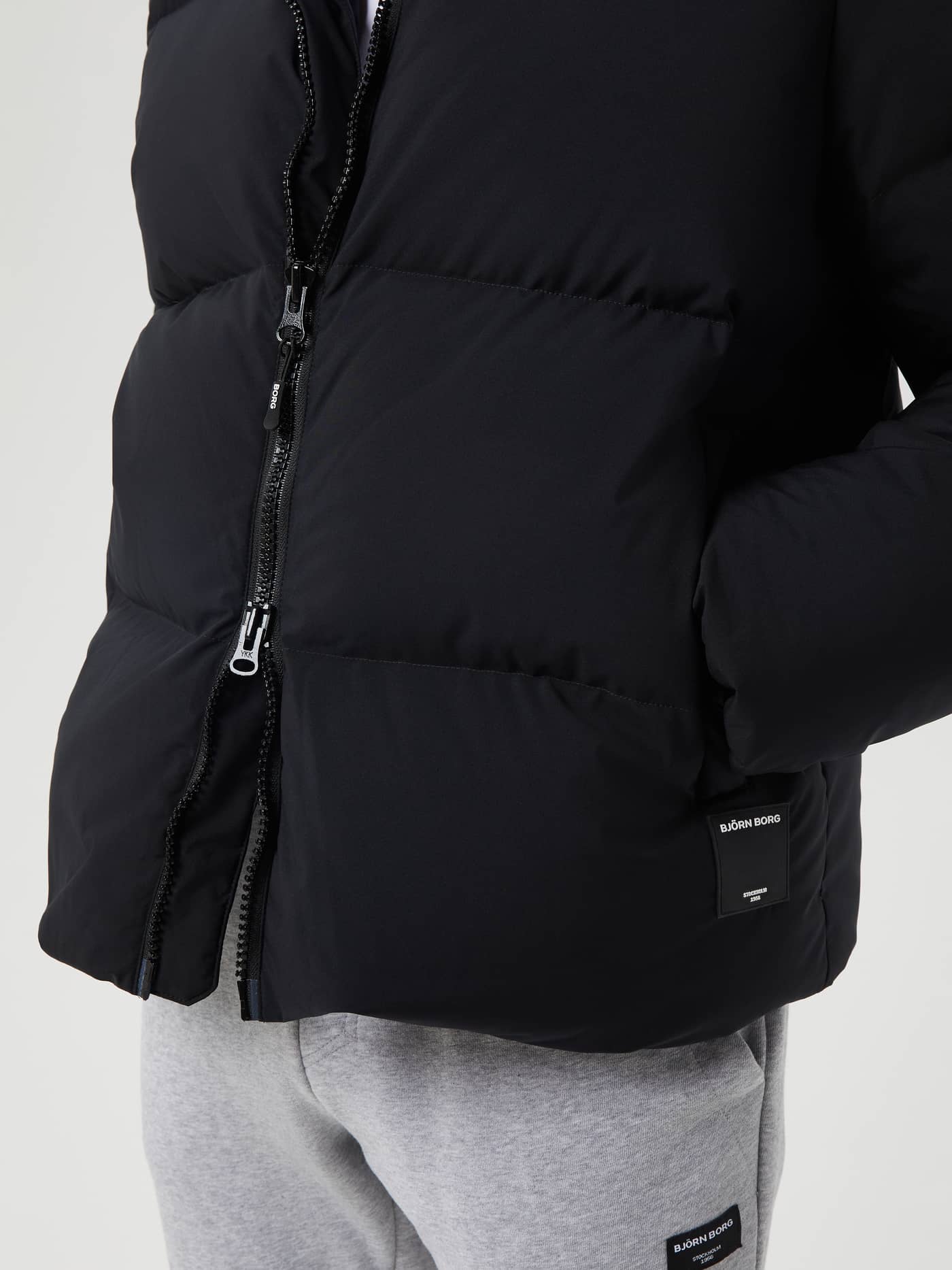 Close-up of the men's Björn Borg Centre Puffer Jacket in Black Beauty (Black) with functional down padding and white logo. - Image 5