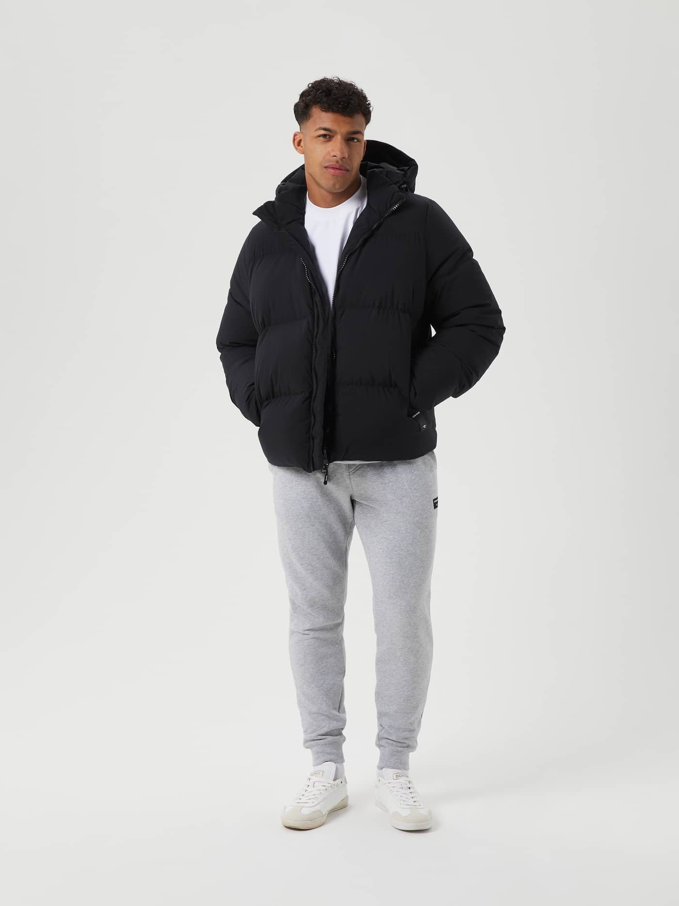 Full-body view of a man in the stylish, functional Björn Borg Centre Puffer Jacket in Black Beauty (Black) with down filling. - Image 1