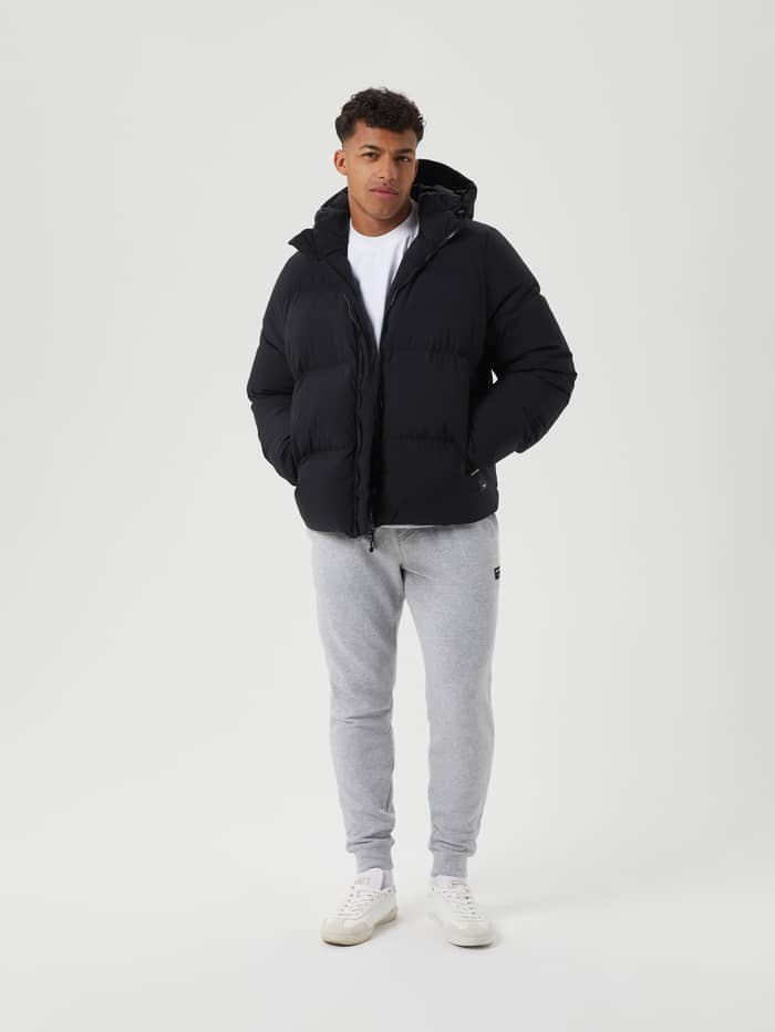 Full-body view of a man in the stylish, functional Björn Borg Centre Puffer Jacket in Black Beauty (Black) with down filling. - Image 1