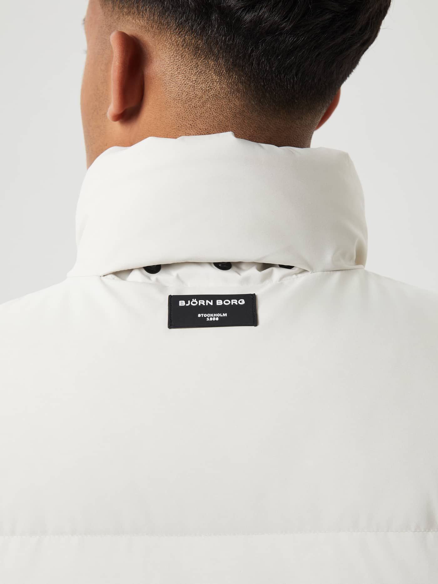Back view of the Björn Borg Centre Puffer Jacket in Silver Birch (White) featuring a black logo patch. - Image 8