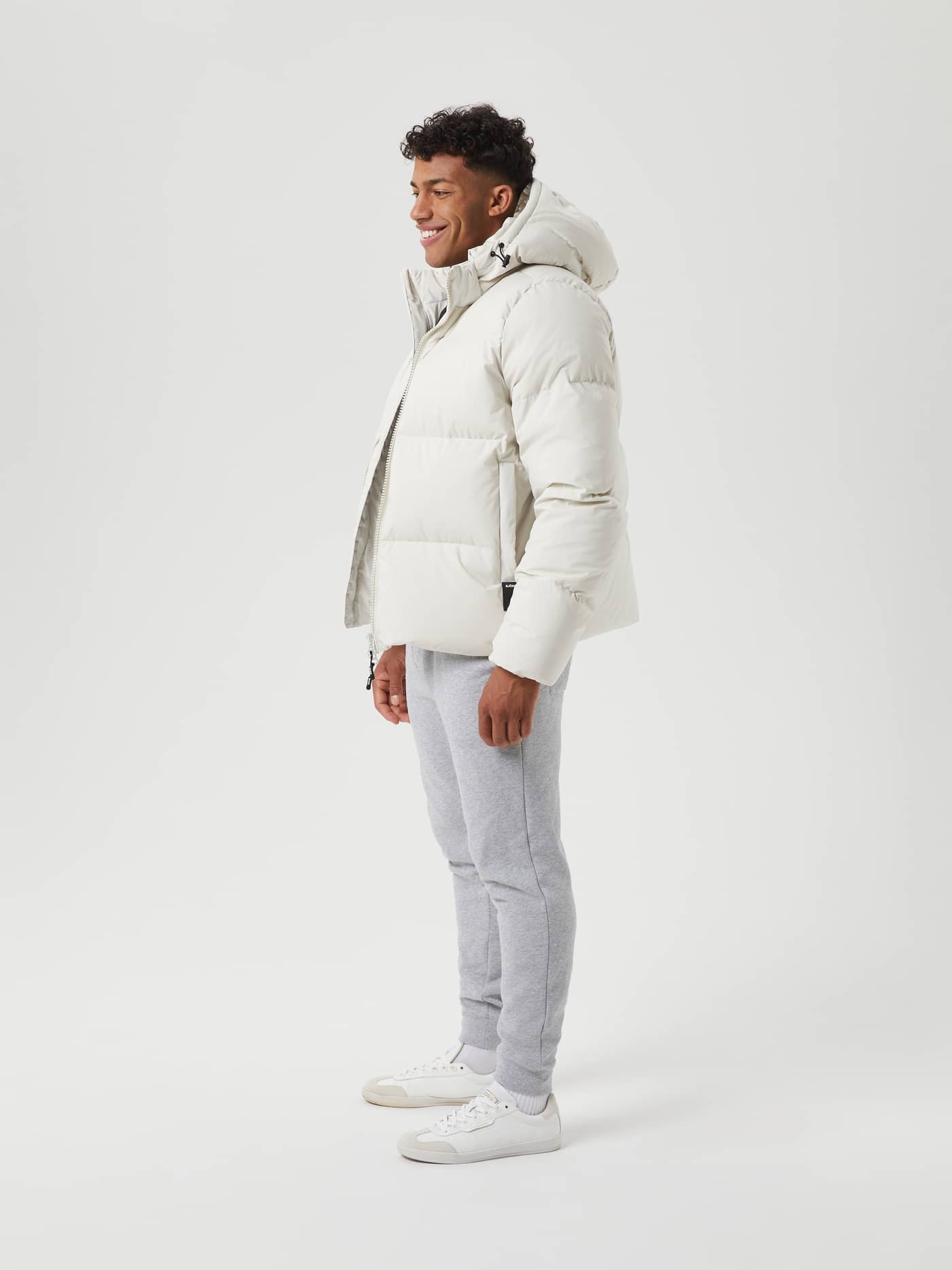 Side view of a man wearing the stylish Björn Borg Centre Puffer Jacket in Silver Birch (White) with functional down padding. - Image 2