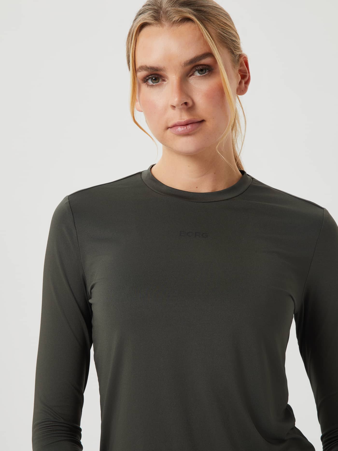Primer plano de mujer con la Borg Long Sleeve T-Shirt en Peat (Verde), cuello redondo, logo sutil y ajuste de entrenamiento. - Image 4