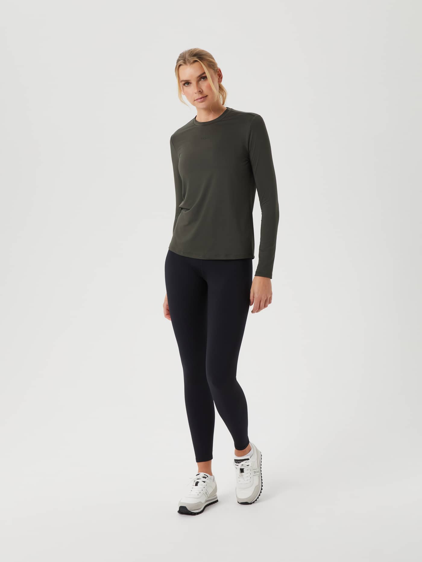 Vista frontal de una modelo con la Borg Long Sleeve T-Shirt en Peat (Verde), leggings negros y un ajuste de entrenamiento. - Image 3