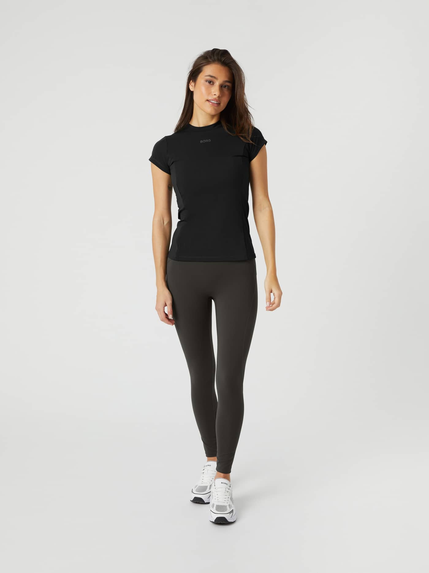 Full-body front view of a woman wearing the slim-fit Borg Reform Premium Tights in Peat (Green) for gym training. - Image 1