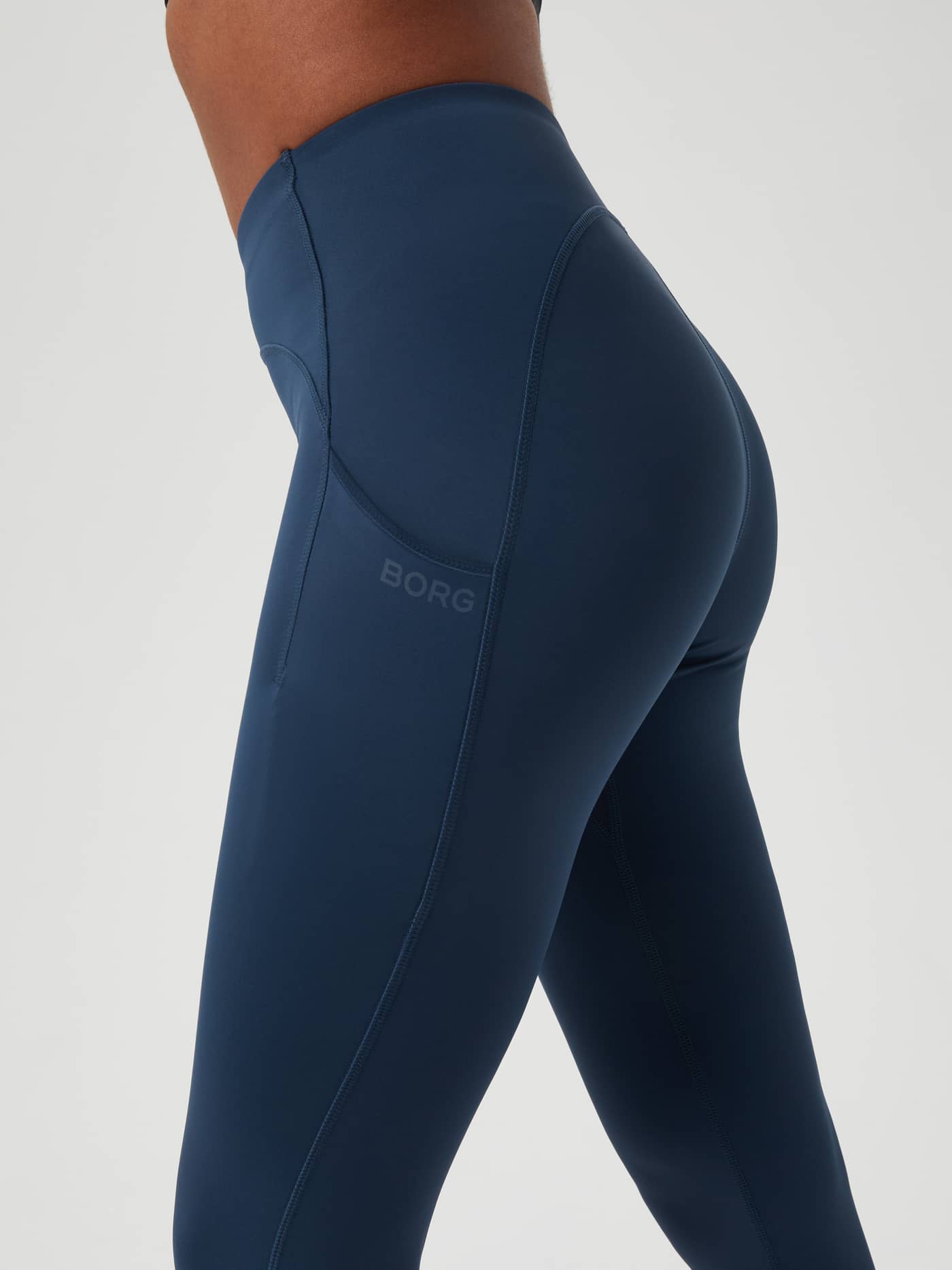 Zijaanzicht van de Borg Reform Premium Tights in Midnight Navy (Blauw) met tonaal logo en telefoonzakje voor training. - Image 4