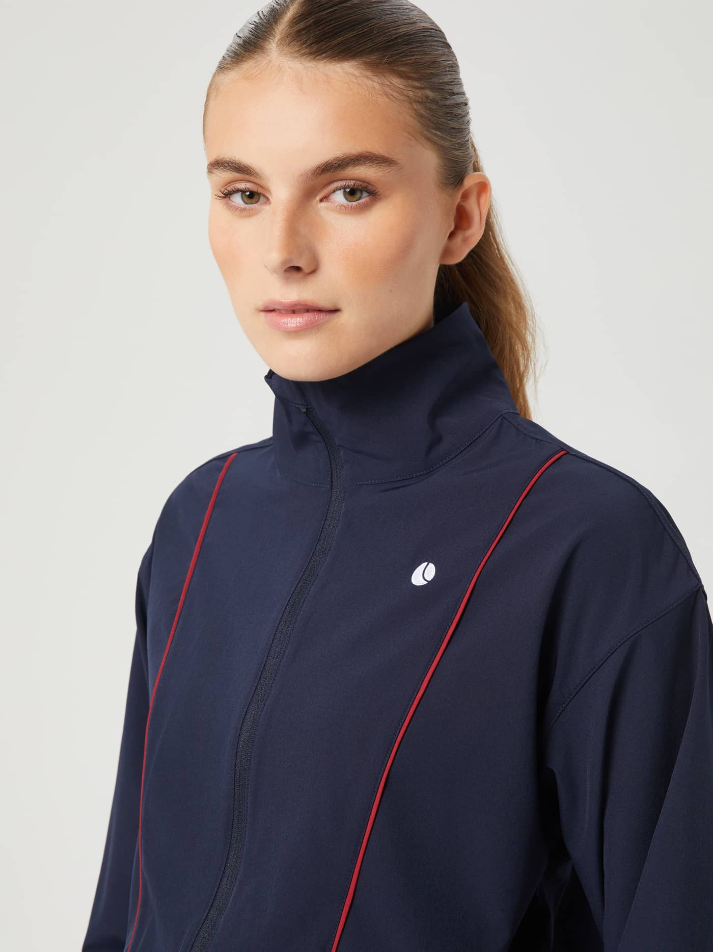 Ace Woven Track Jacket i Night sky (marineblå) med hvit tennisball-logo, vist i et nærbilde av modell for tennis. - Image 5