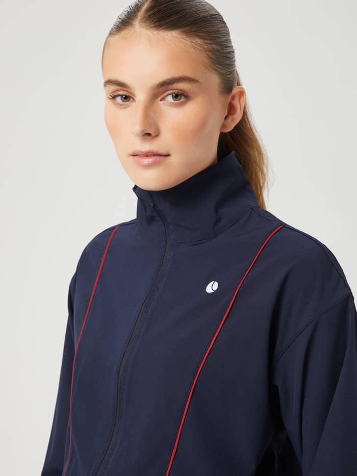 Nahaufnahme der Ace Woven Track Jacket in Night sky (Dunkelblau) mit weißem Tennisball-Logo, perfekt für Tennis. - Image 5