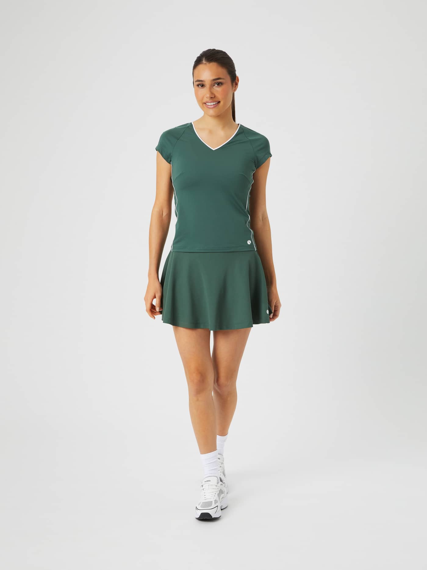 Slim-fit Björn Borg Ace V T-Shirt in Cilantro (Groen) met een tennisrokje, getoond in een volledig vooraanzicht. - Image 4