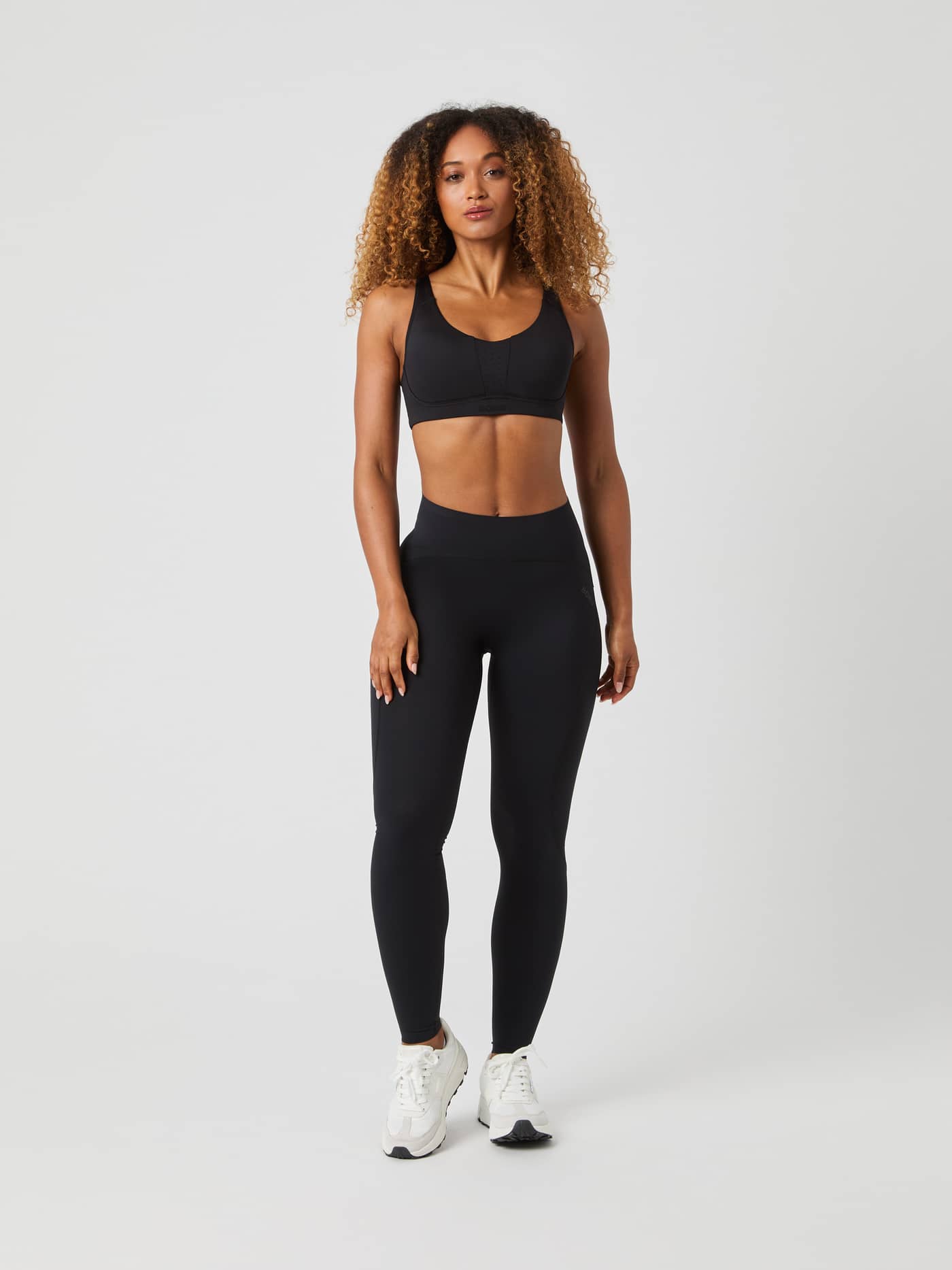 Full length studio shot of a woman facing forward, wearing the black Borg Reform Sports Bra with matching leggings. - Image 4