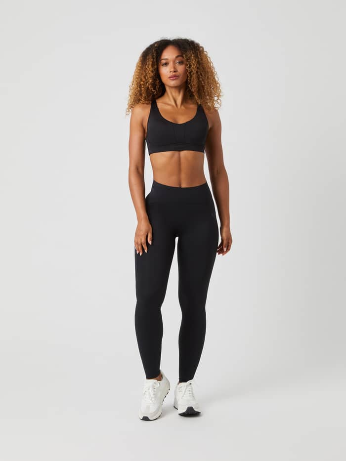 Full length studio shot of a woman facing forward, wearing the black Borg Reform Sports Bra with matching leggings. - Image 4