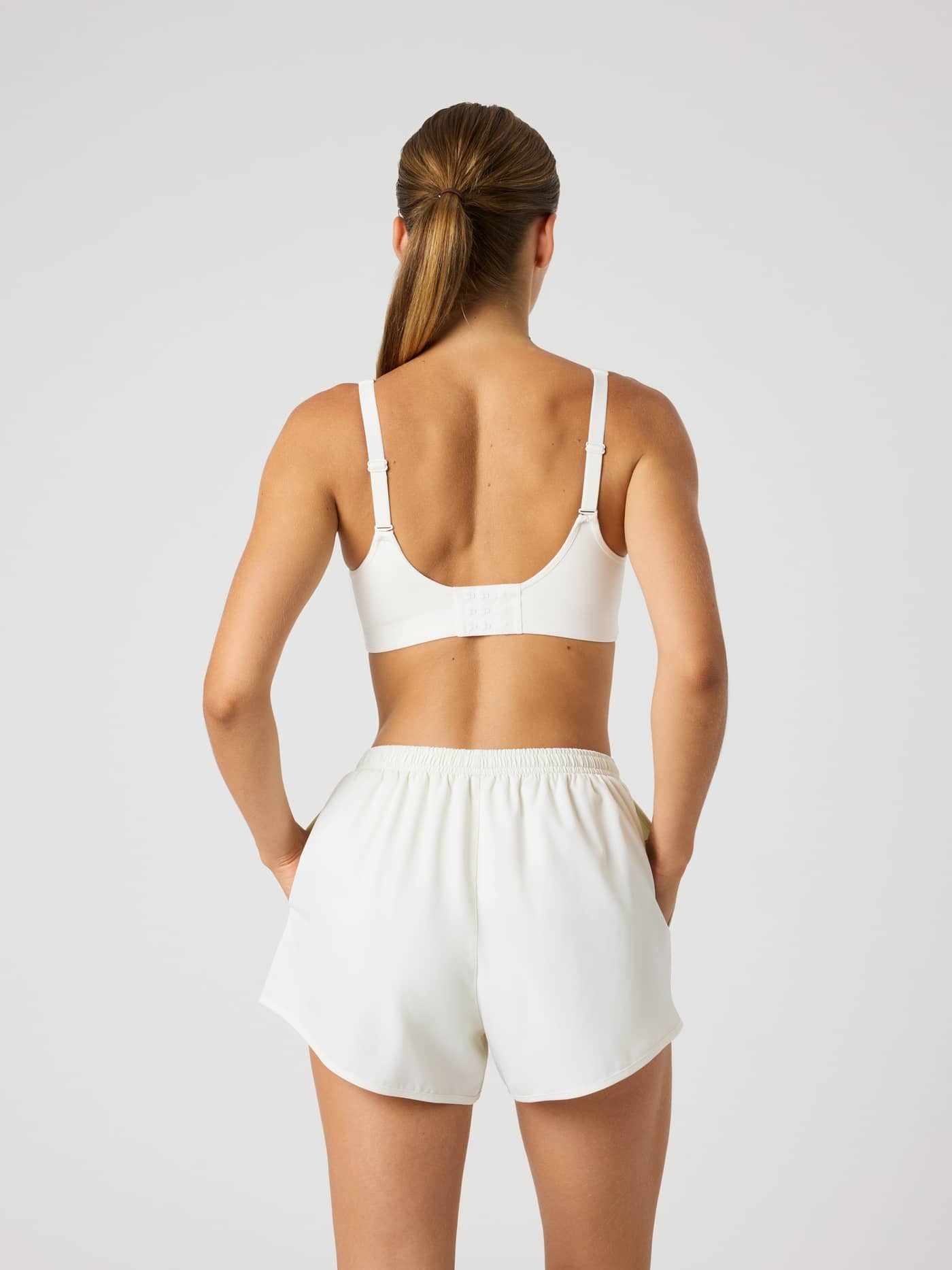 Back view of a woman wearing the Björn Borg Reform Sports Bra in Tofu (White), with adjustable straps for a performance fit. - Image 5