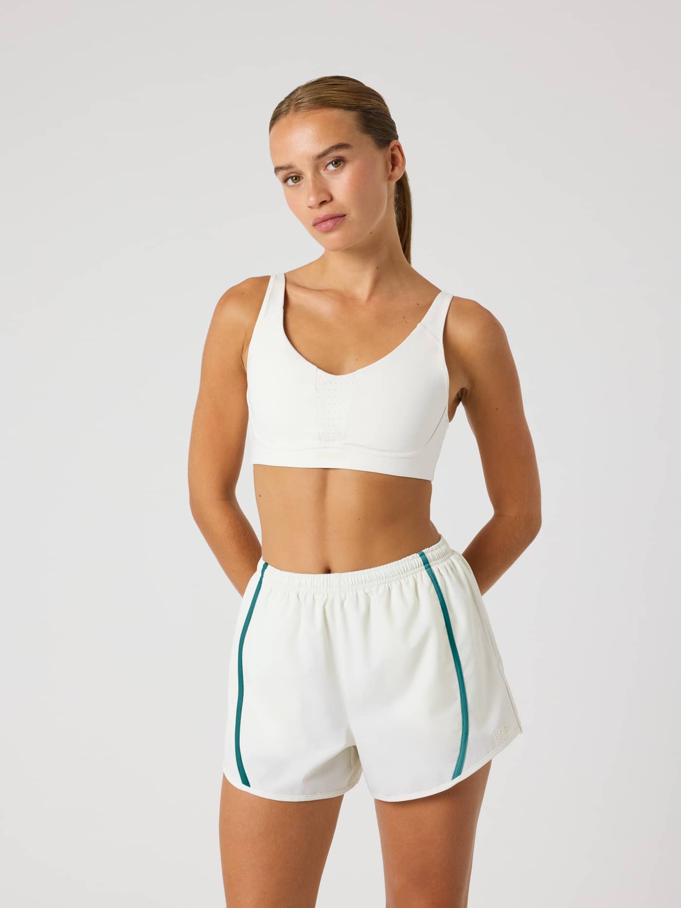 Front view of a woman wearing the Borg Reform Sports Bra in Tofu (White), a training style with a medium-support fit. - Image 4