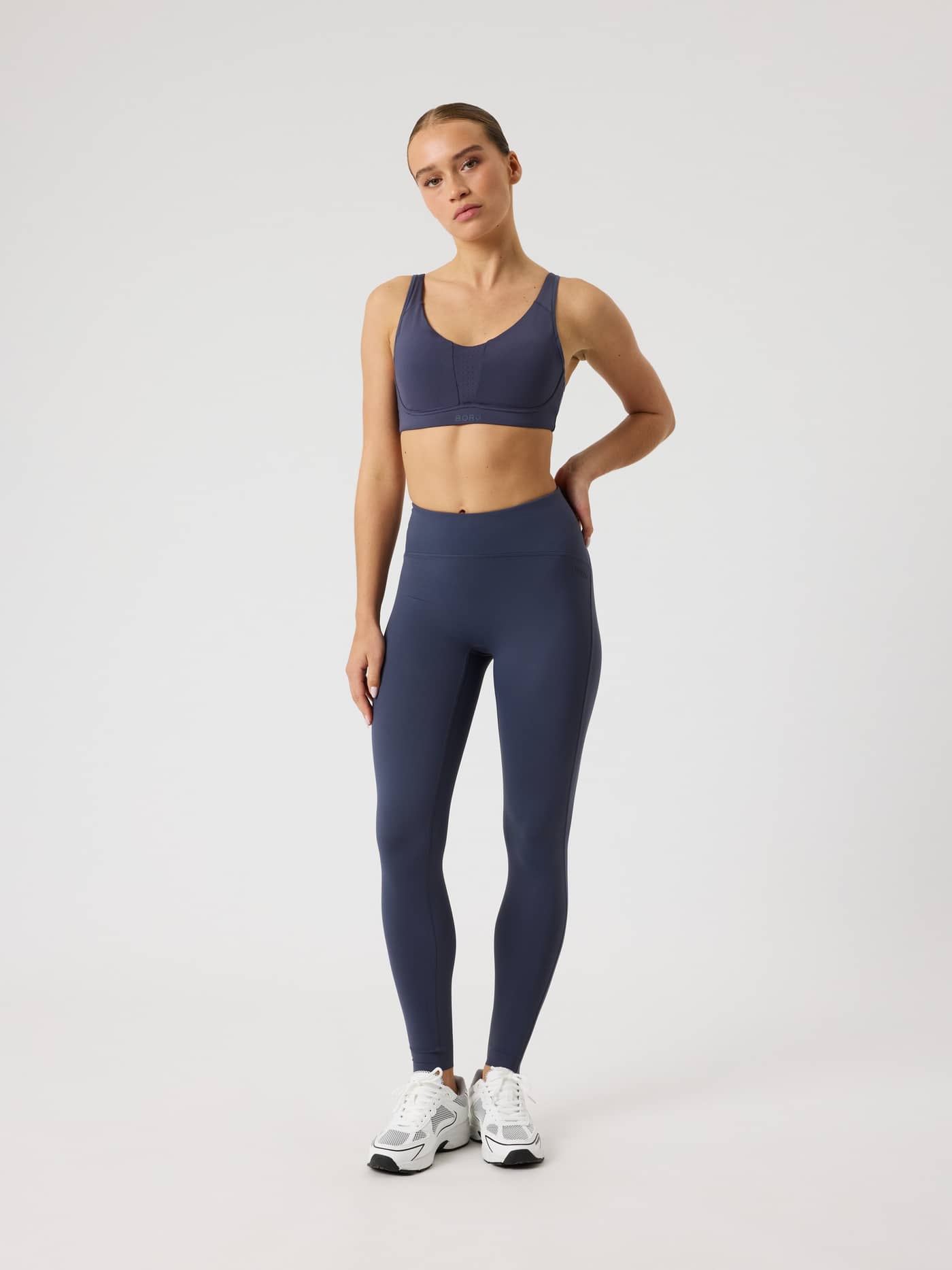 Full-body front view of a woman in the navy Borg Reform Sports Bra, providing a stylish and supportive fit for training. - Image 3
