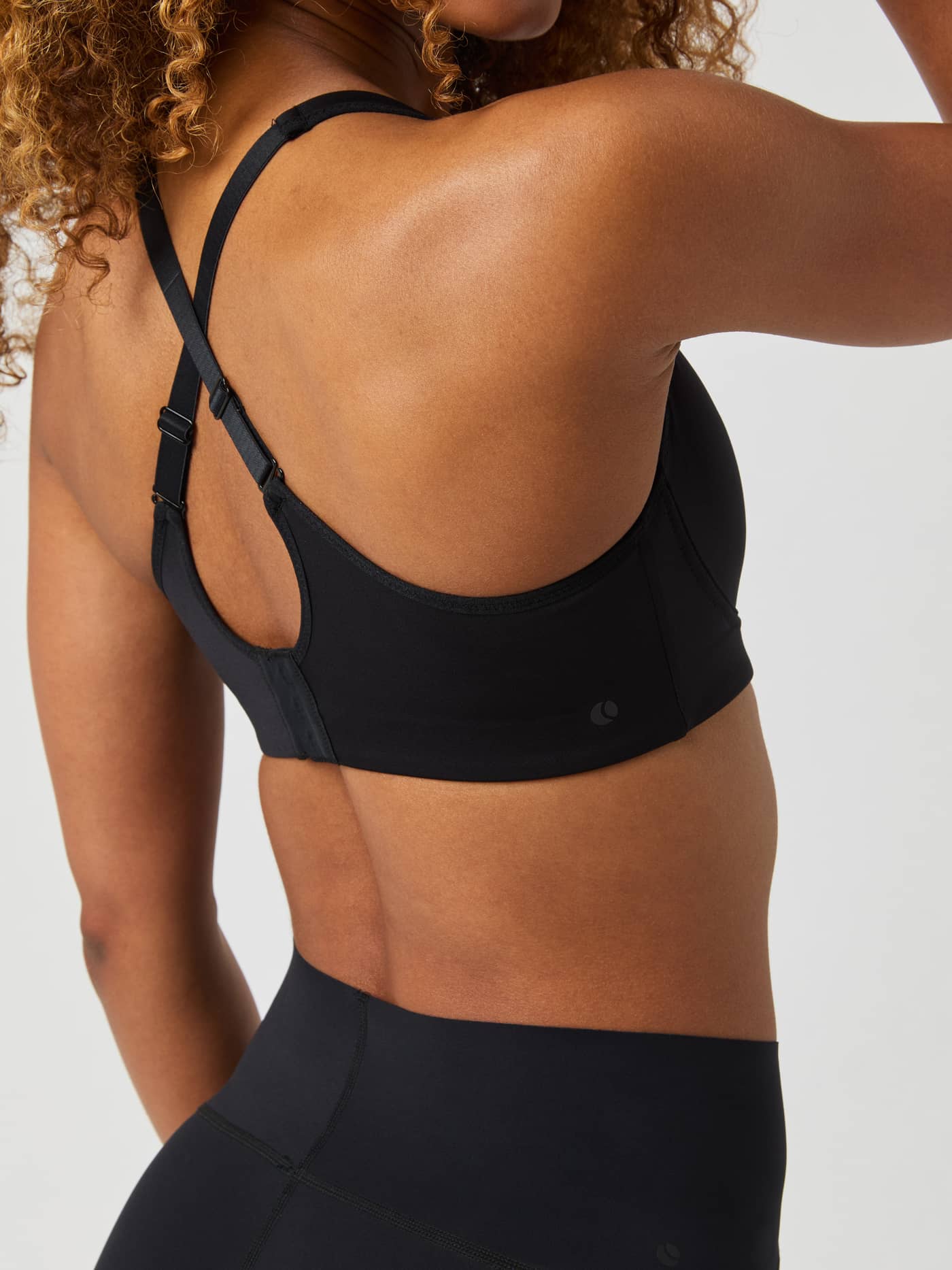 Back view of a model wearing the black Borg Reform Sports Bra, showing the adjustable straps and hook-and-eye closure. - Image 3