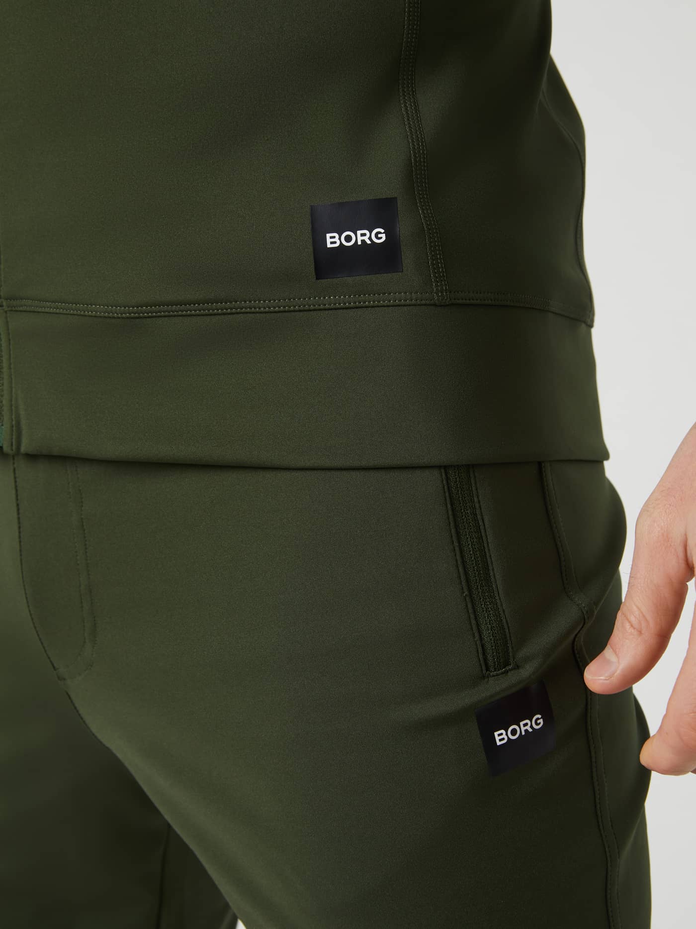 Close-up of the Duffel Bag (Green) Borg Training Midlayer Jacket for men, showcasing the logo and functional style. - Image 4