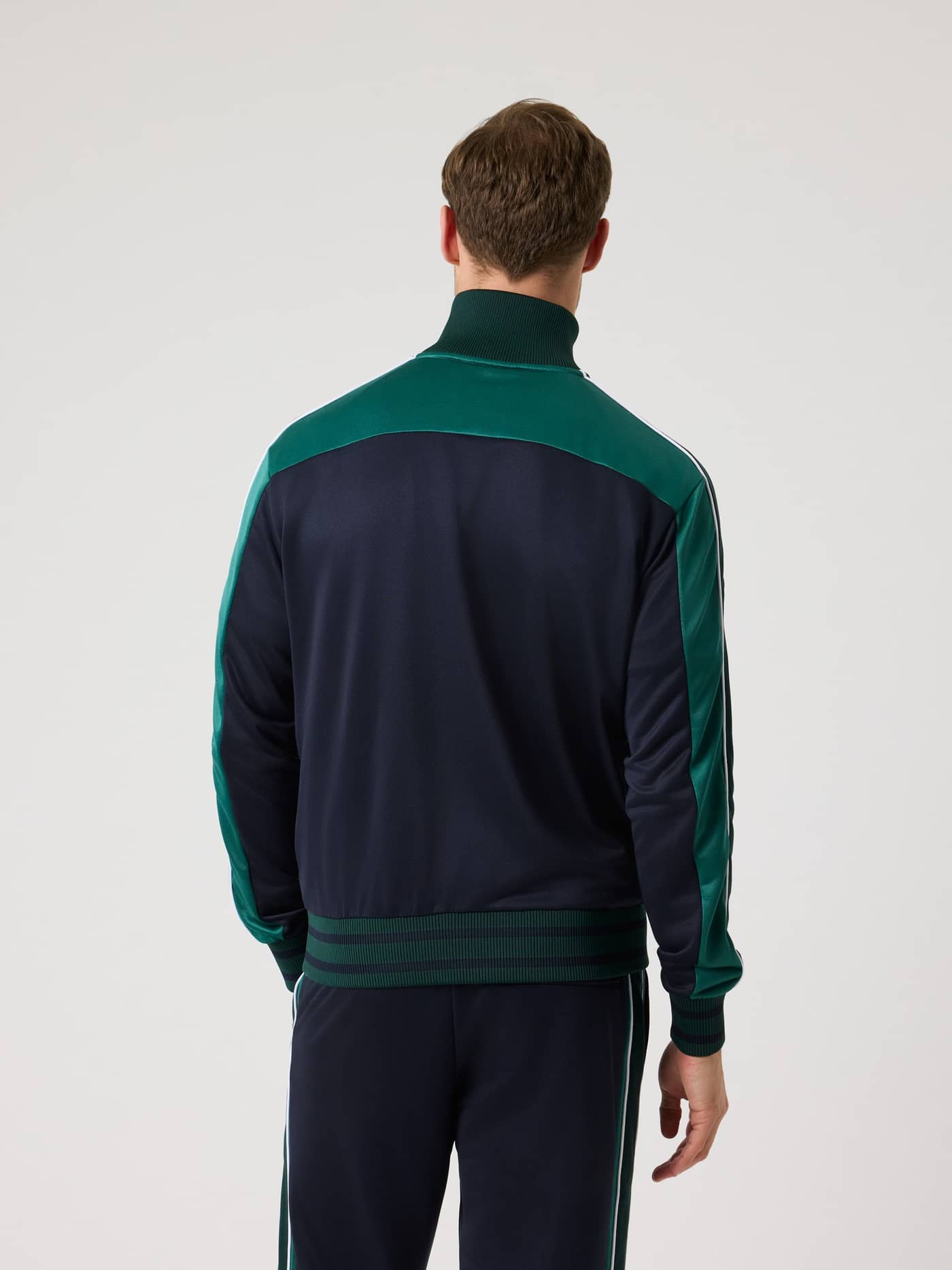 Back view of a man wearing the Björn Borg Ace Retro Track Jacket in Night sky (Navy), a performance tennis jacket. - Image 2