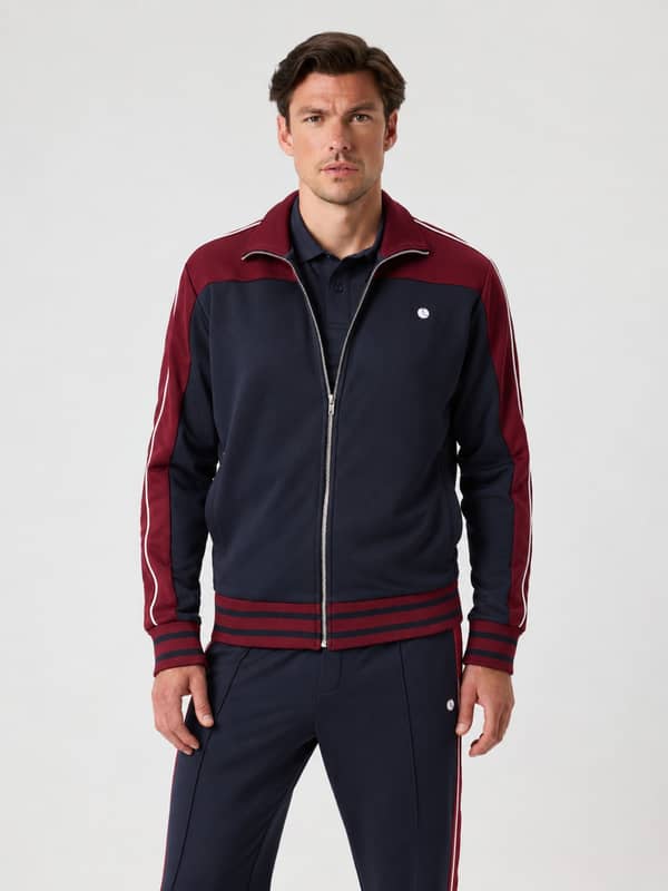 Vooraanzicht van een model met de Ace Retro Track Jacket in Night sky (navy) voor tennis, met contrasterende panelen.