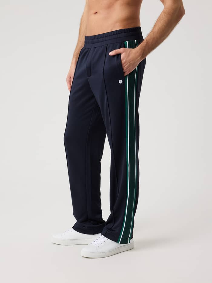 Ace Retro Track Pants in Night sky (Navy) in recycled polyester with a white tennis logo for functional style, worn by a man.