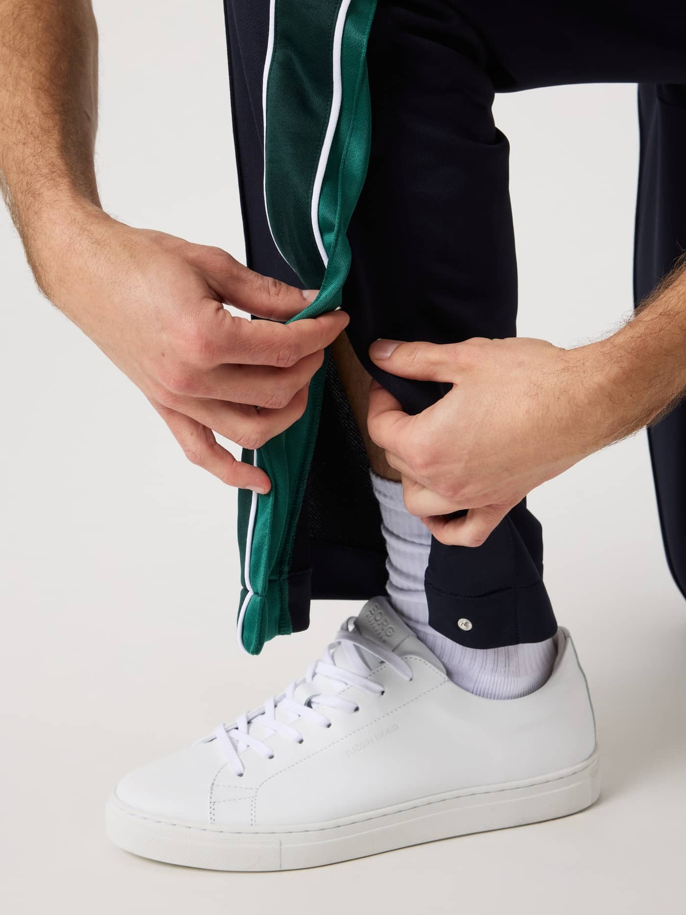 Nærbillede af Ace Retro Track Pants i Night sky (Marineblå) med grønt panel og trykknapper i benslidser til tennis. - Image 6