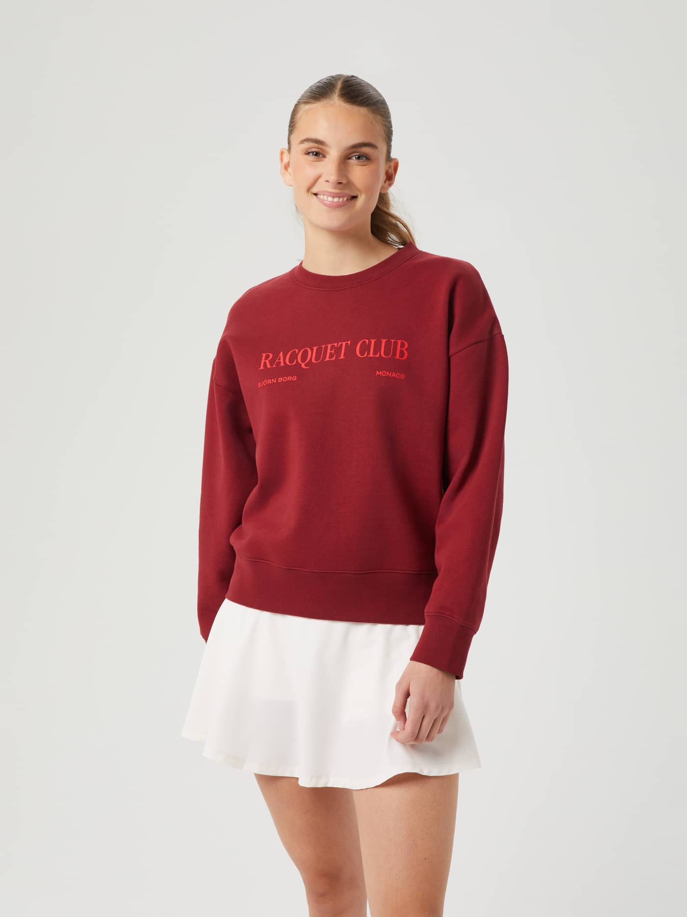 Front view of a model wearing the Pomegranate (Red) Borg Boyfriend Crew, a stylish oversized fleece with a tennis graphic. - Image 2