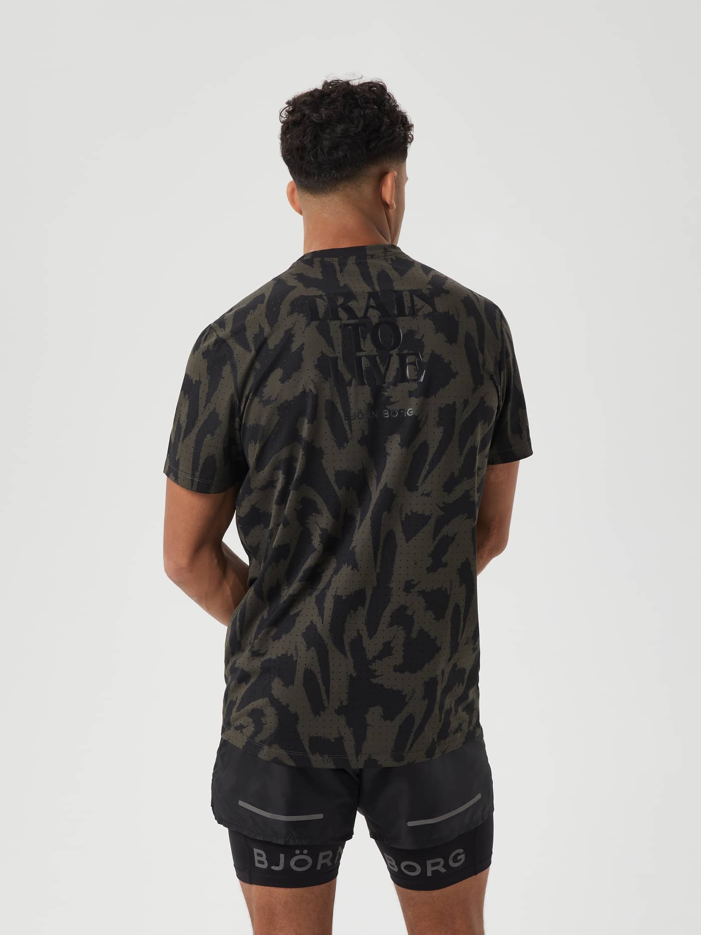 Back view of a man in the green and black Borg Running Perforated T-Shirt with a black graphic print for running. - Image 2